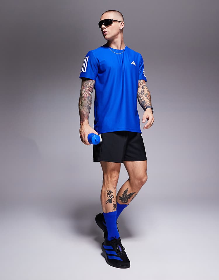 Man wearing adidas Adizero Evo SL sneakers with black shorts and blue shirt holding a water bottle