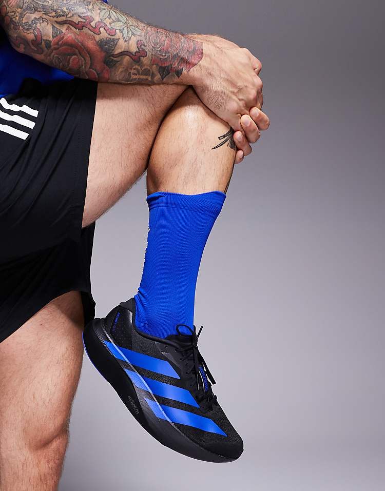 Close-up of adidas Adizero Evo SL sneakers in black with blue stripes worn by a man with blue socks