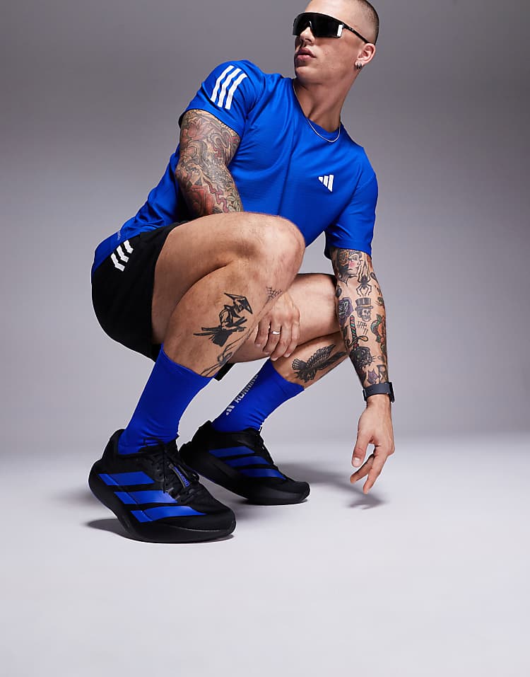 Man wearing adidas Adizero Evo SL sneakers in black with blue stripes and matching blue athletic outfit