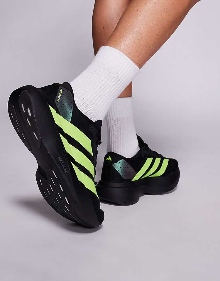 Black and neon green adidas Adizero Evo SL sneakers worn with white crew socks for men