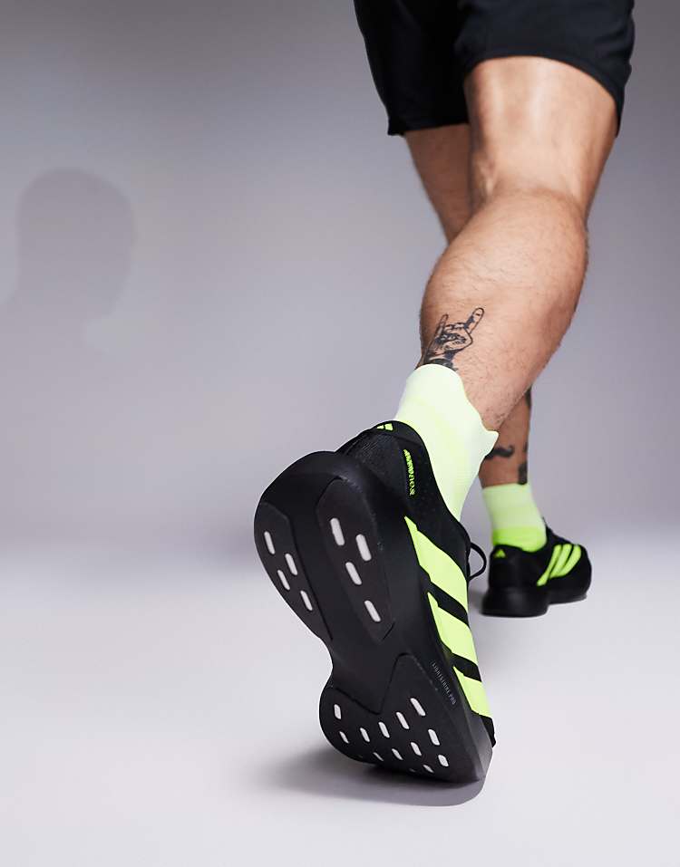 Man wearing black and neon green adidas Adizero Evo SL sneakers from Modan Online in an active pose