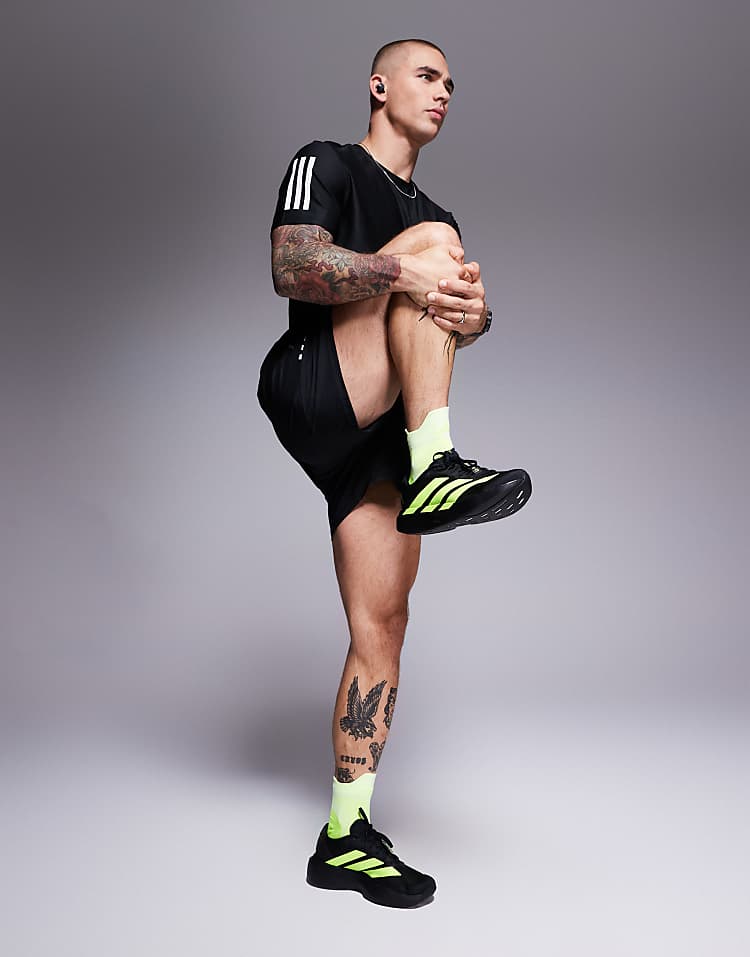 Man stretching wearing black adidas Adizero Evo SL sneakers with neon yellow accents and matching socks