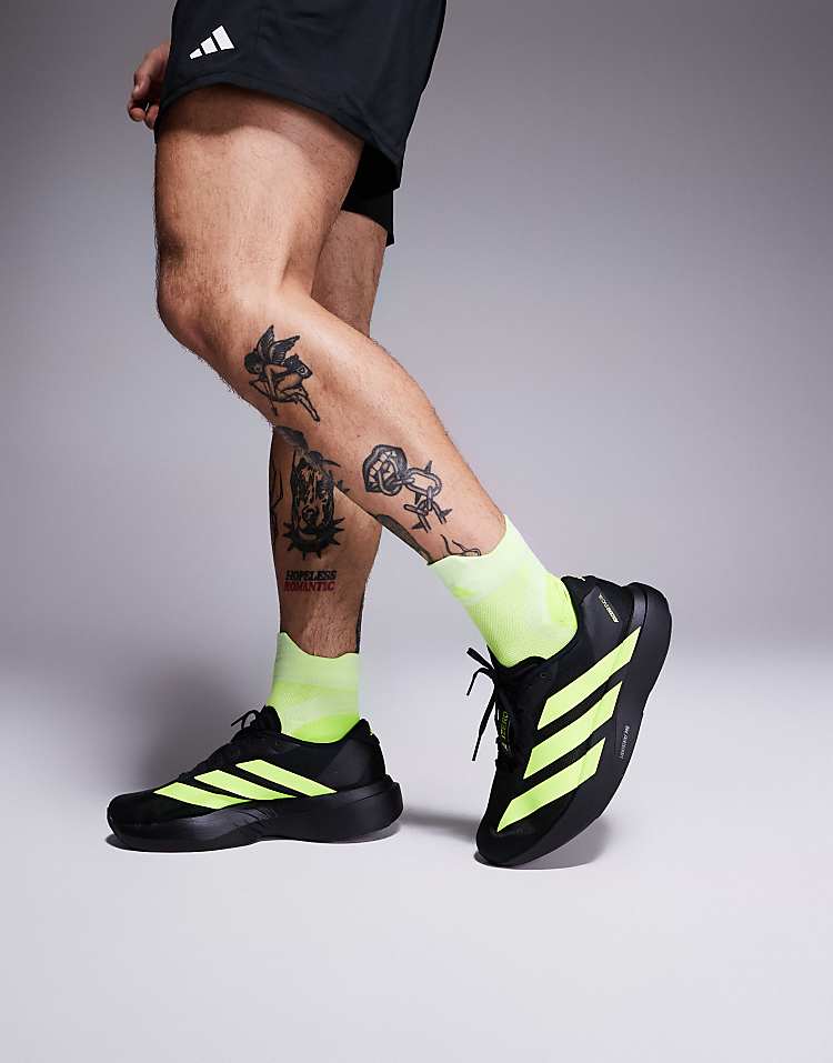 Men wearing adidas Adizero Evo SL sneakers in black with neon yellow stripes and matching neon yellow socks