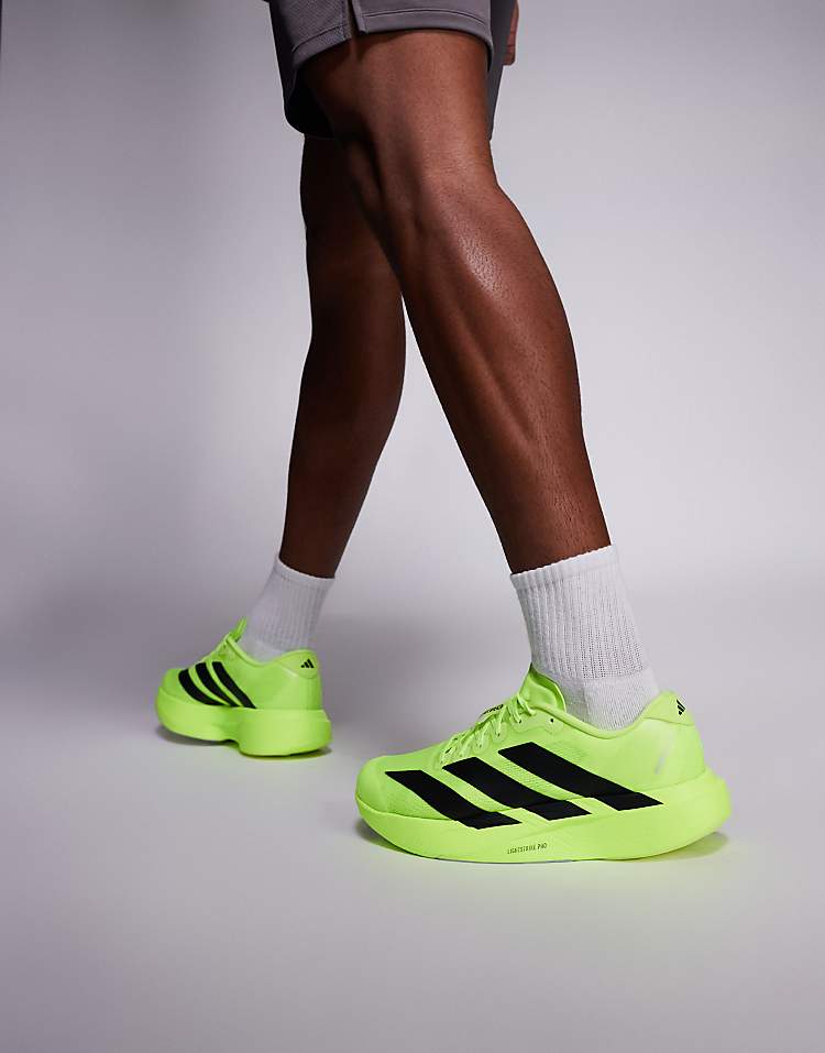 Bright green adidas Adizero Evo SL sneakers with black stripes worn by a man with white socks