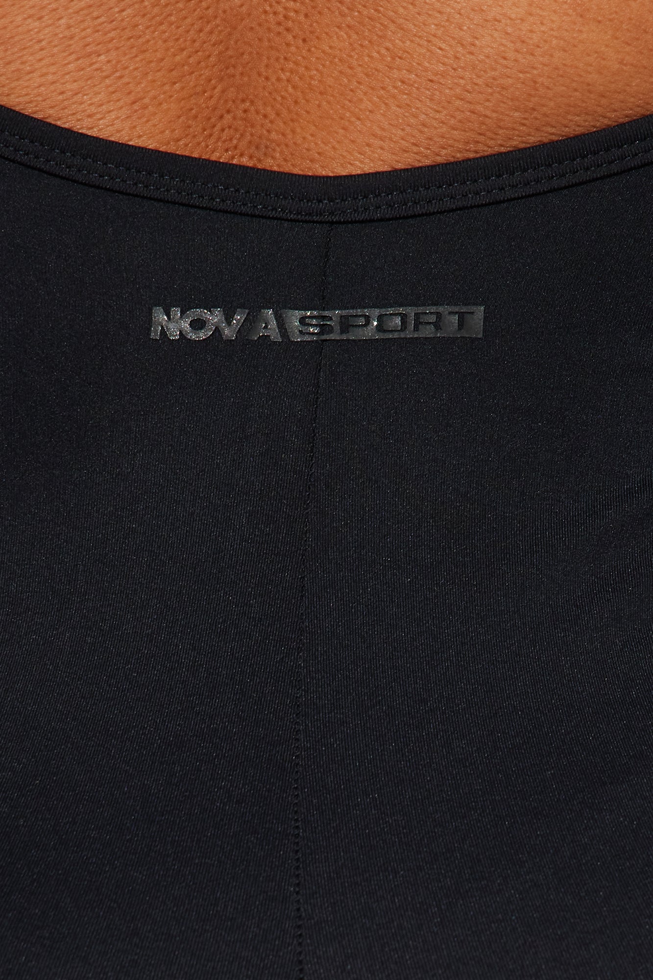 Nova Sport logo detail on a sleek black active jumpsuit for women with a sporty design