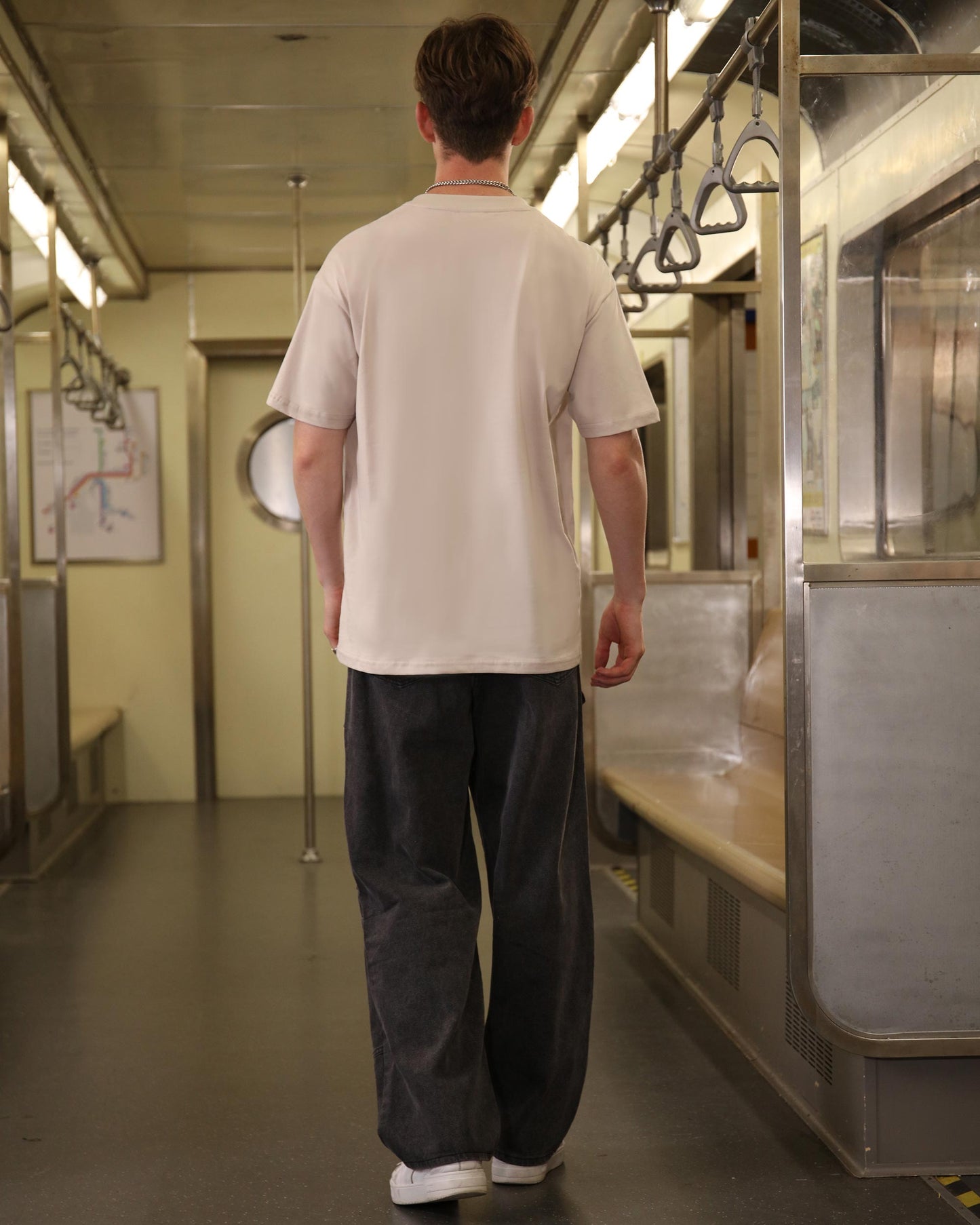 Man wearing black baggy jeans with pockets by Logeqi standing inside subway train