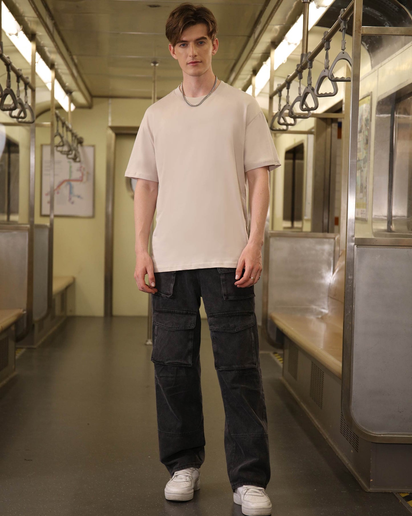 Logeqi black baggy jeans with pockets worn by male model in subway setting with casual beige t-shirt