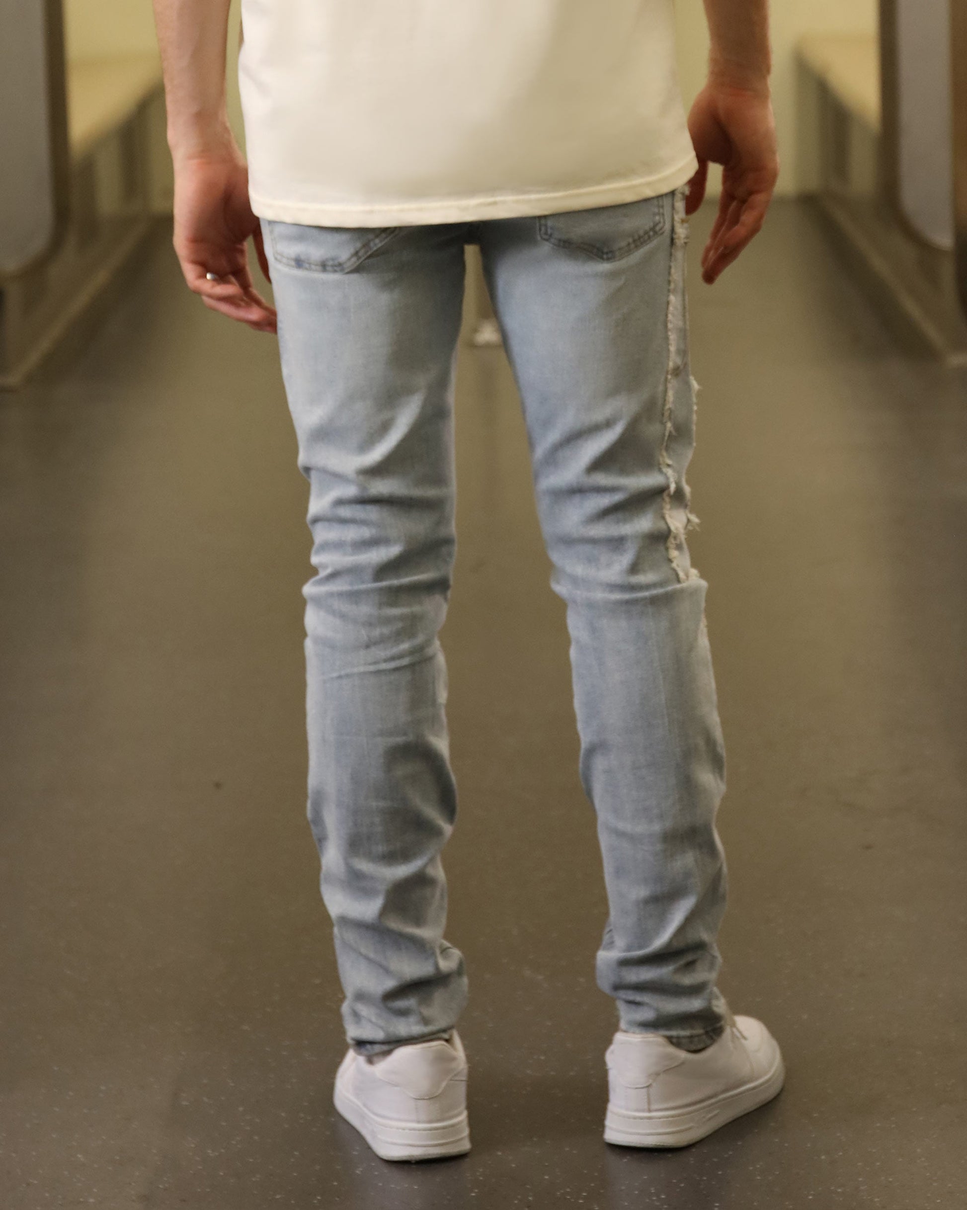 Rear view of blue jeans with diamond accents by Logeqi worn with white sneakers and a white shirt