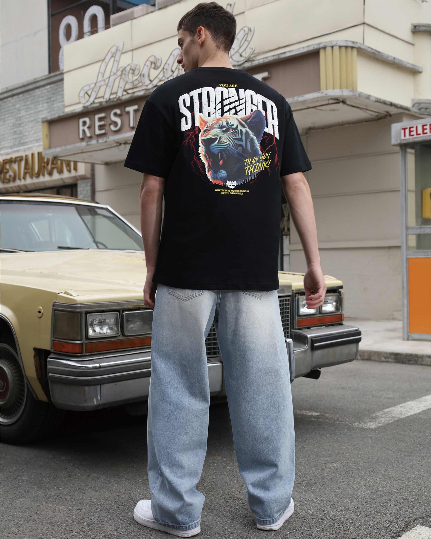 Logeqi blue ripped baggy jeans worn by man standing near vintage car on city street