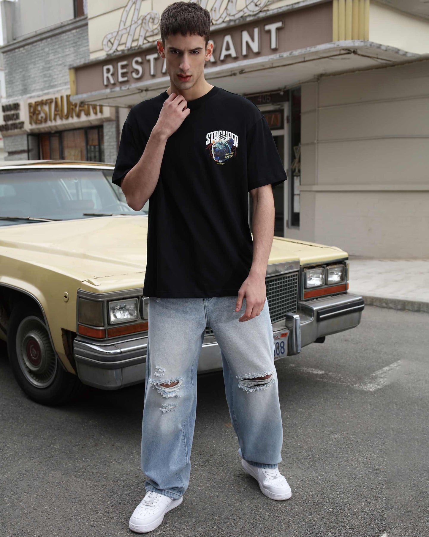 Logeqi blue ripped baggy jeans worn by male model with black graphic t-shirt and white sneakers