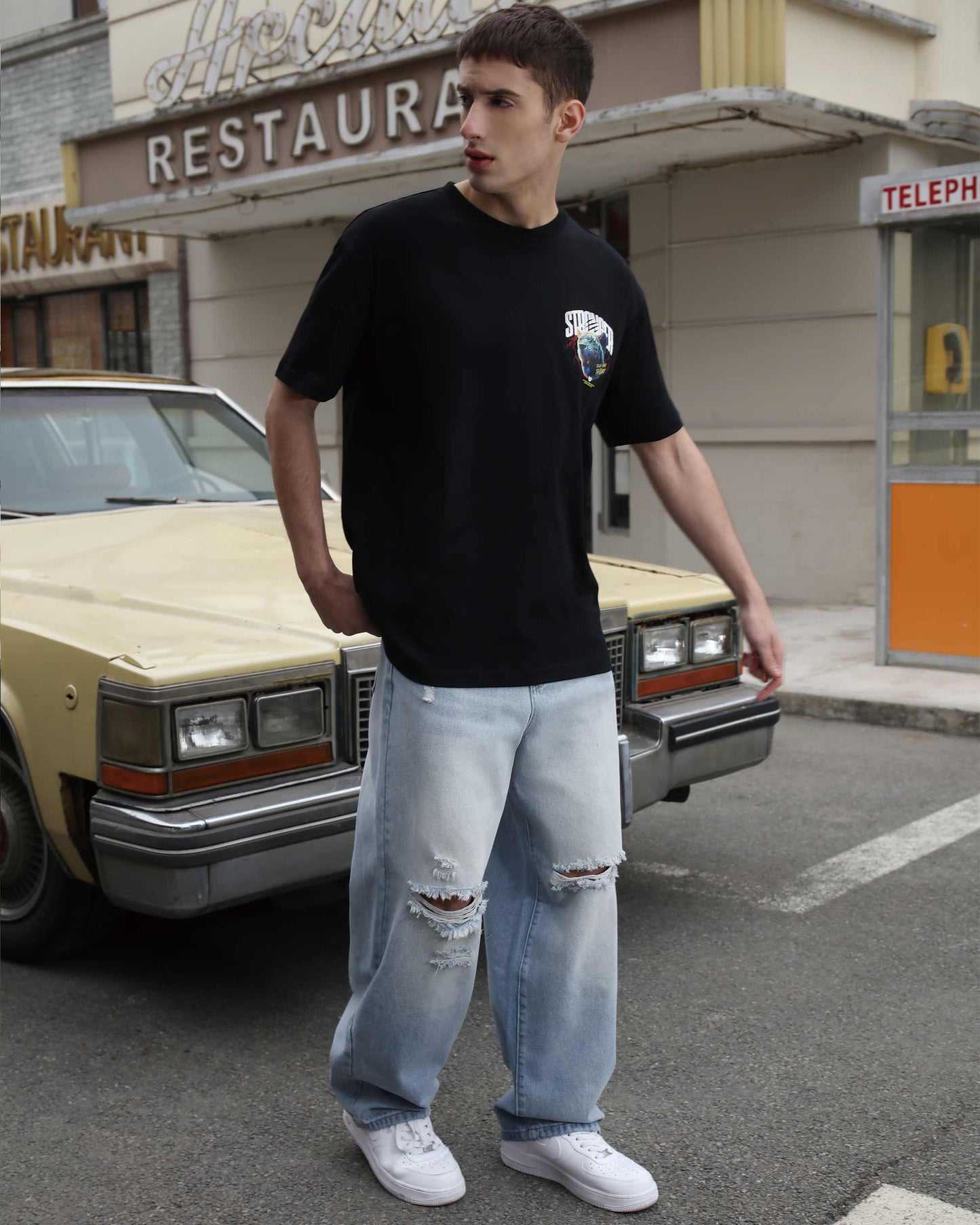 Logeqi blue ripped baggy jeans worn by man standing next to vintage car on street