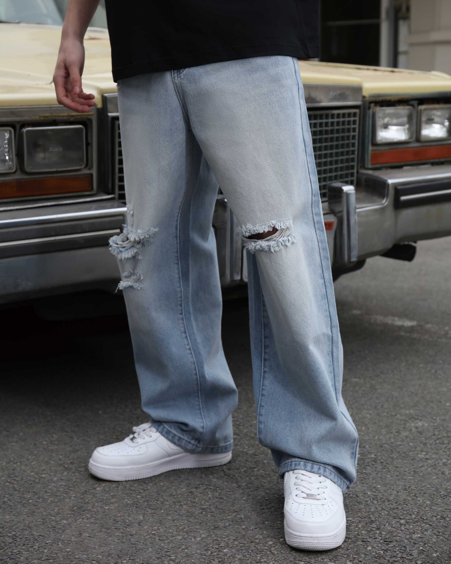 Logeqi blue ripped baggy jeans worn with white sneakers in urban street setting