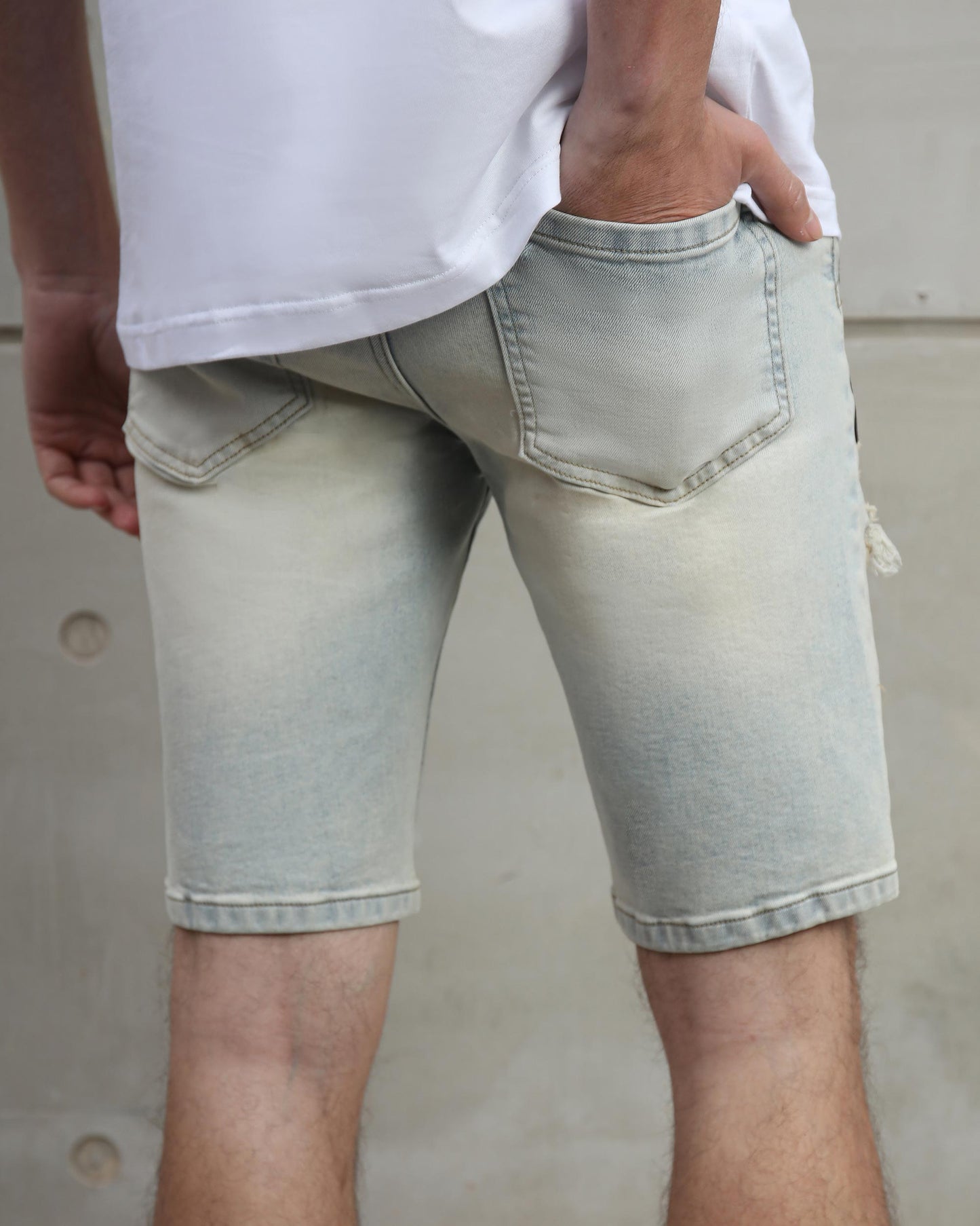 Logeqi distressed graffiti denim shorts light wash worn by a man with hand in pocket from the back