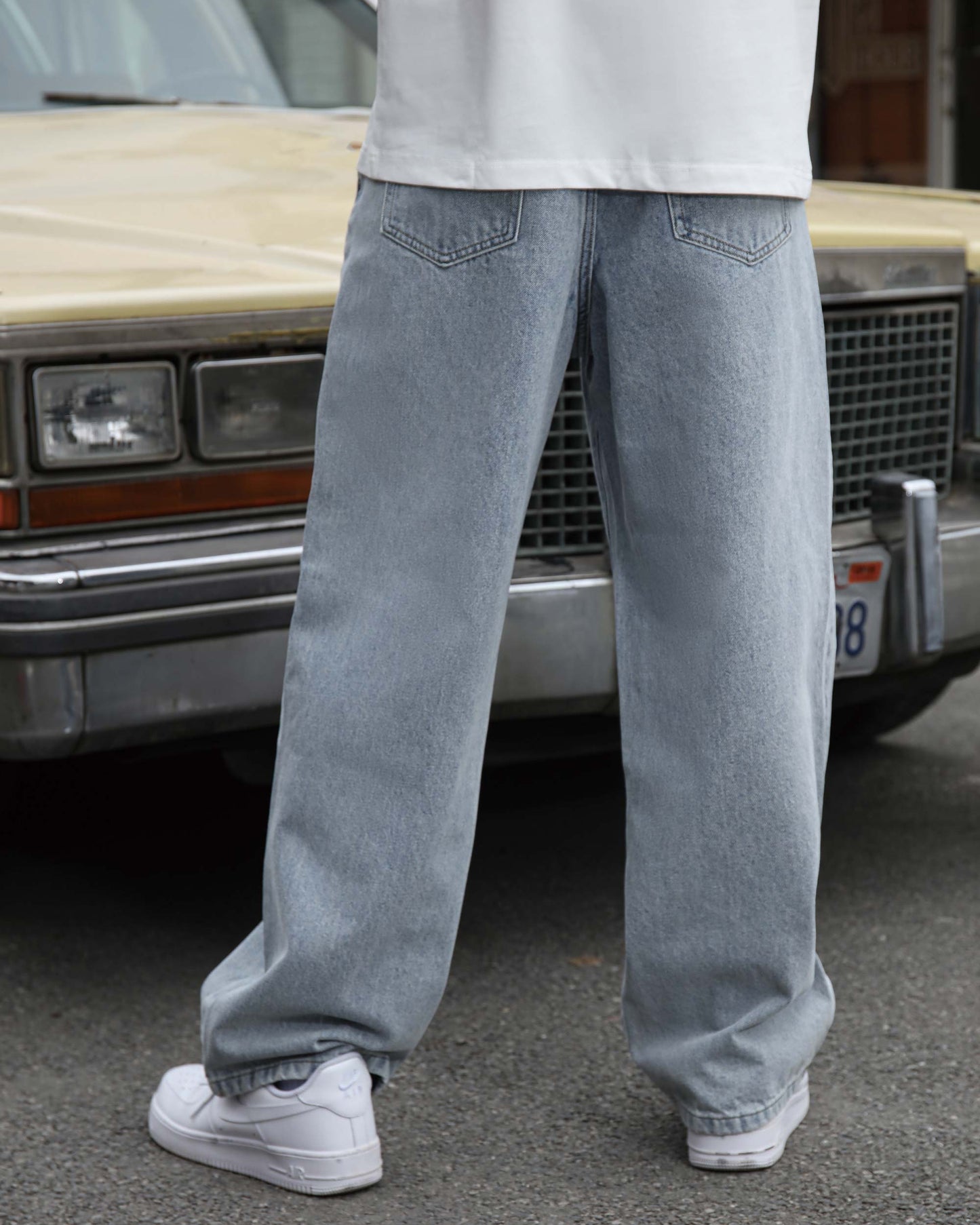 Logeqi loose fit blue jeans worn by model standing in front of vintage car on street