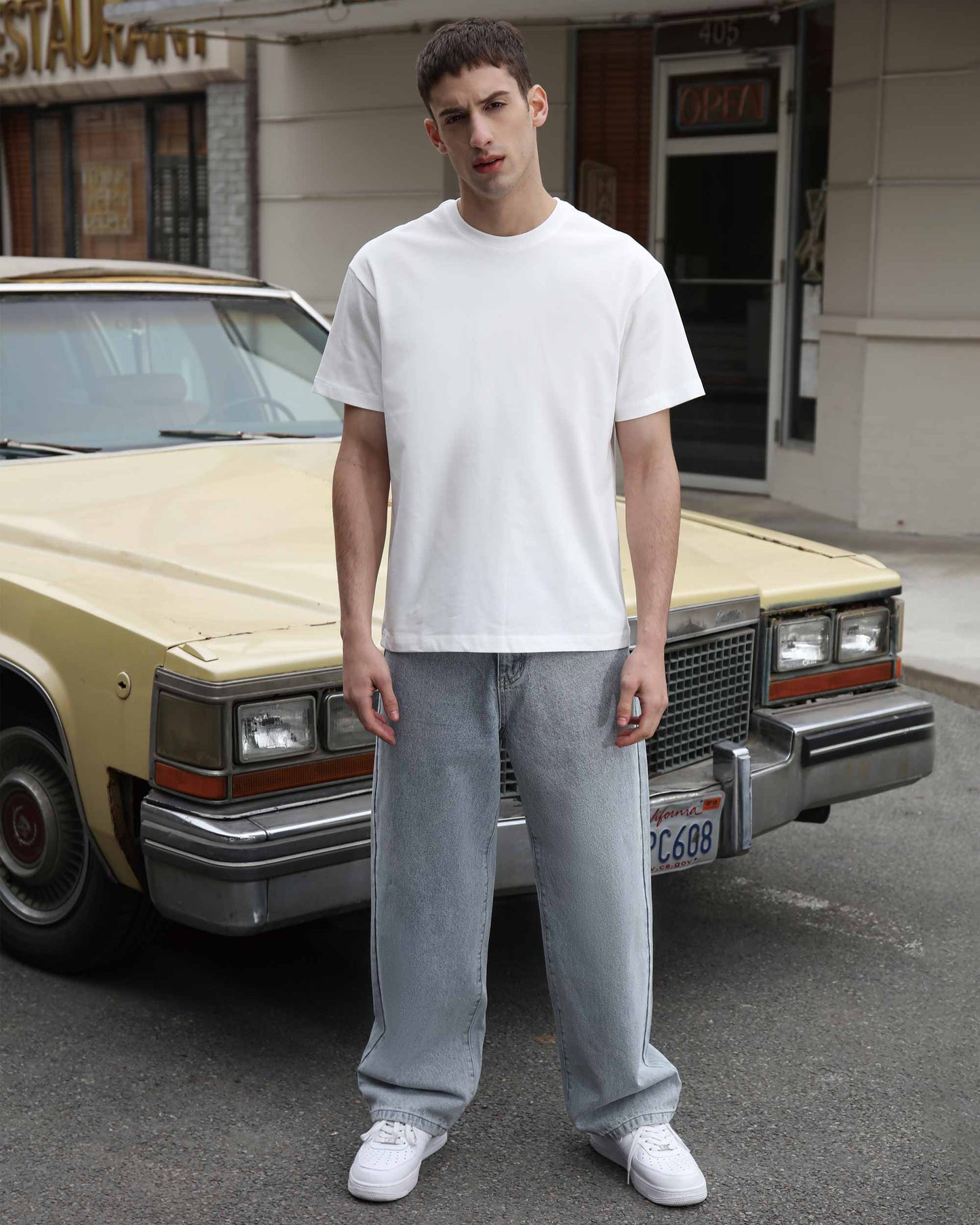 Man wearing Logeqi loose fit blue jeans paired with white t-shirt standing in front of vintage car