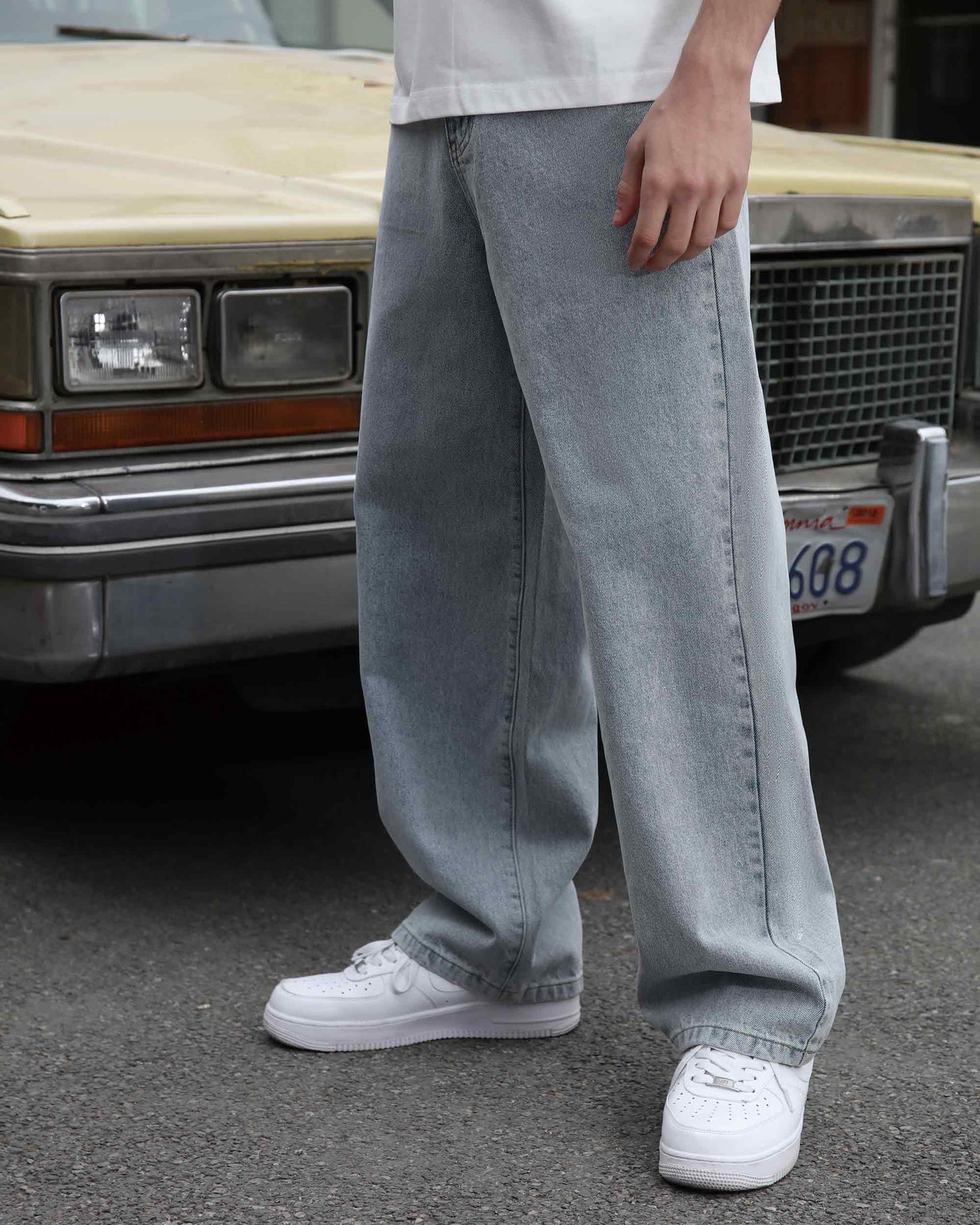 Logeqi loose fit blue jeans worn with white sneakers standing next to vintage car