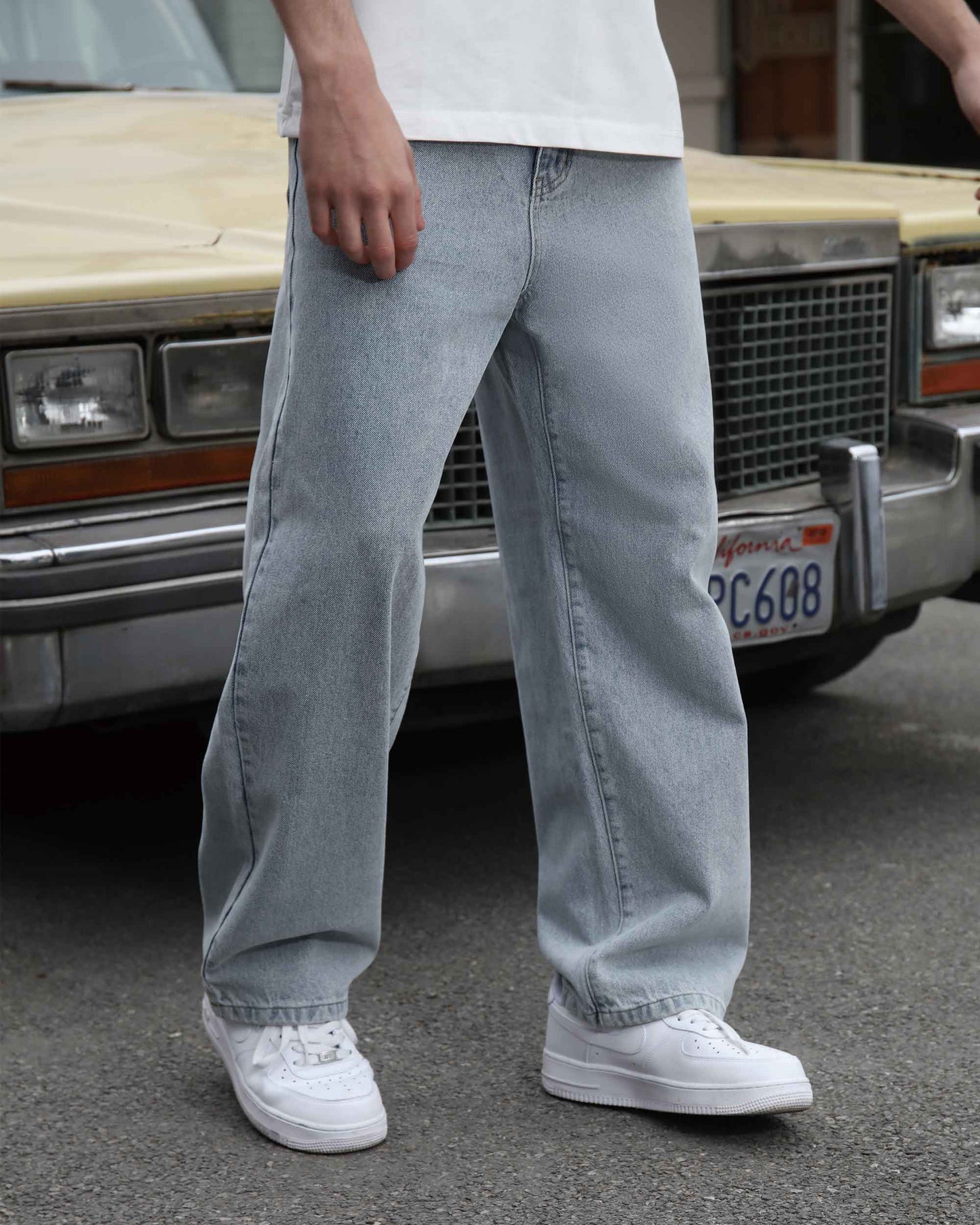 Logeqi loose fit blue jeans worn with white sneakers and a white shirt in urban setting