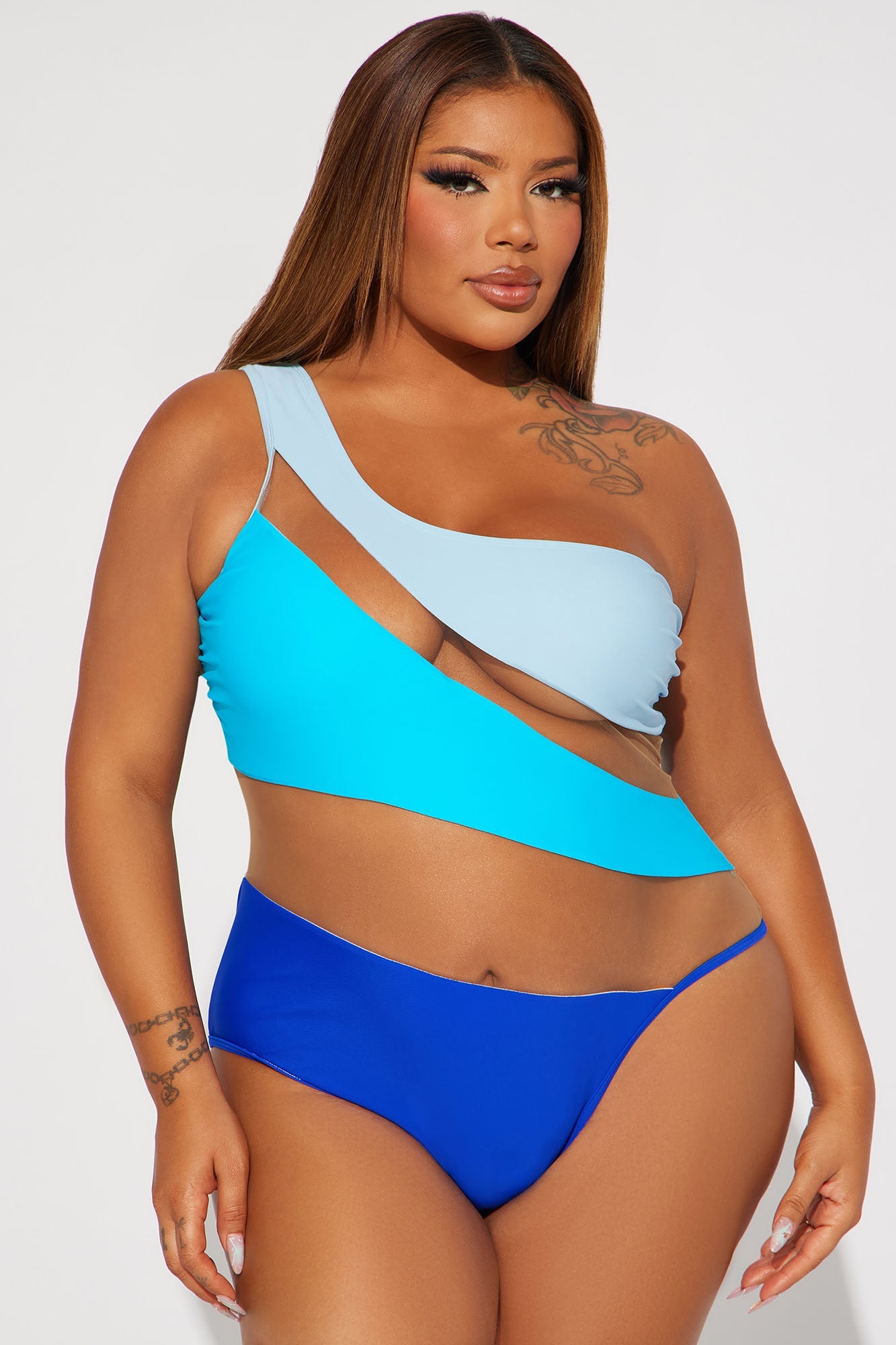 Fashion Nova model wearing a blue colorblock cutout mesh one-piece swimsuit with asymmetrical one-shoulder and diagonal cutouts
