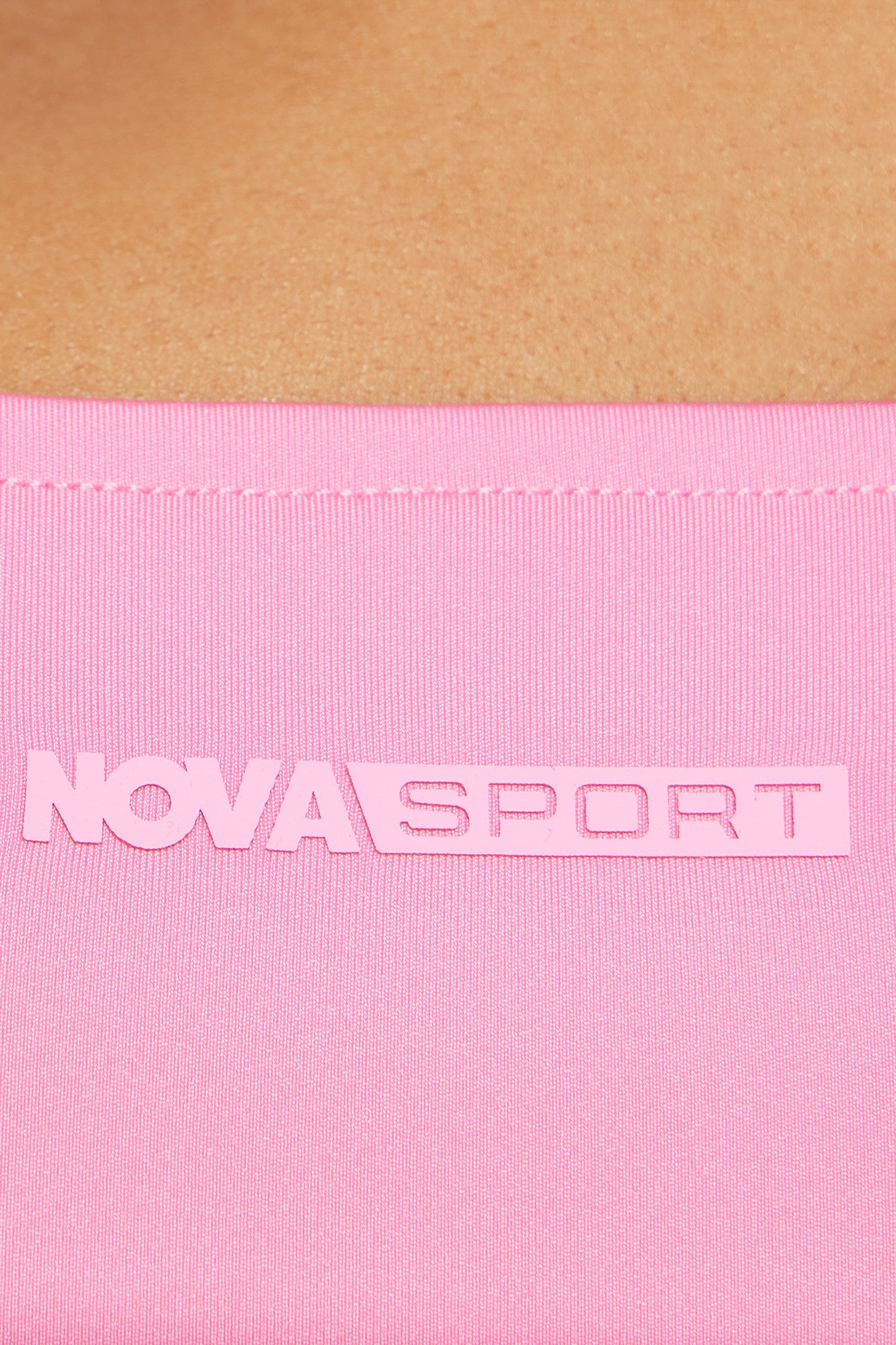 Close-up of Nova Sport logo on bubblegum pink active top highlighting sleek design and vibrant color