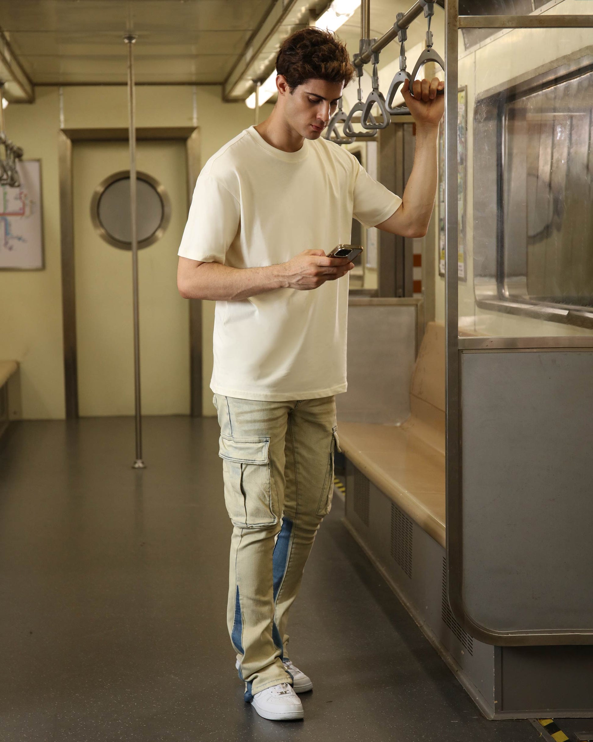 Logeqi industrial style cargo jeans in beige with multiple pockets, worn by a young man in a subway
