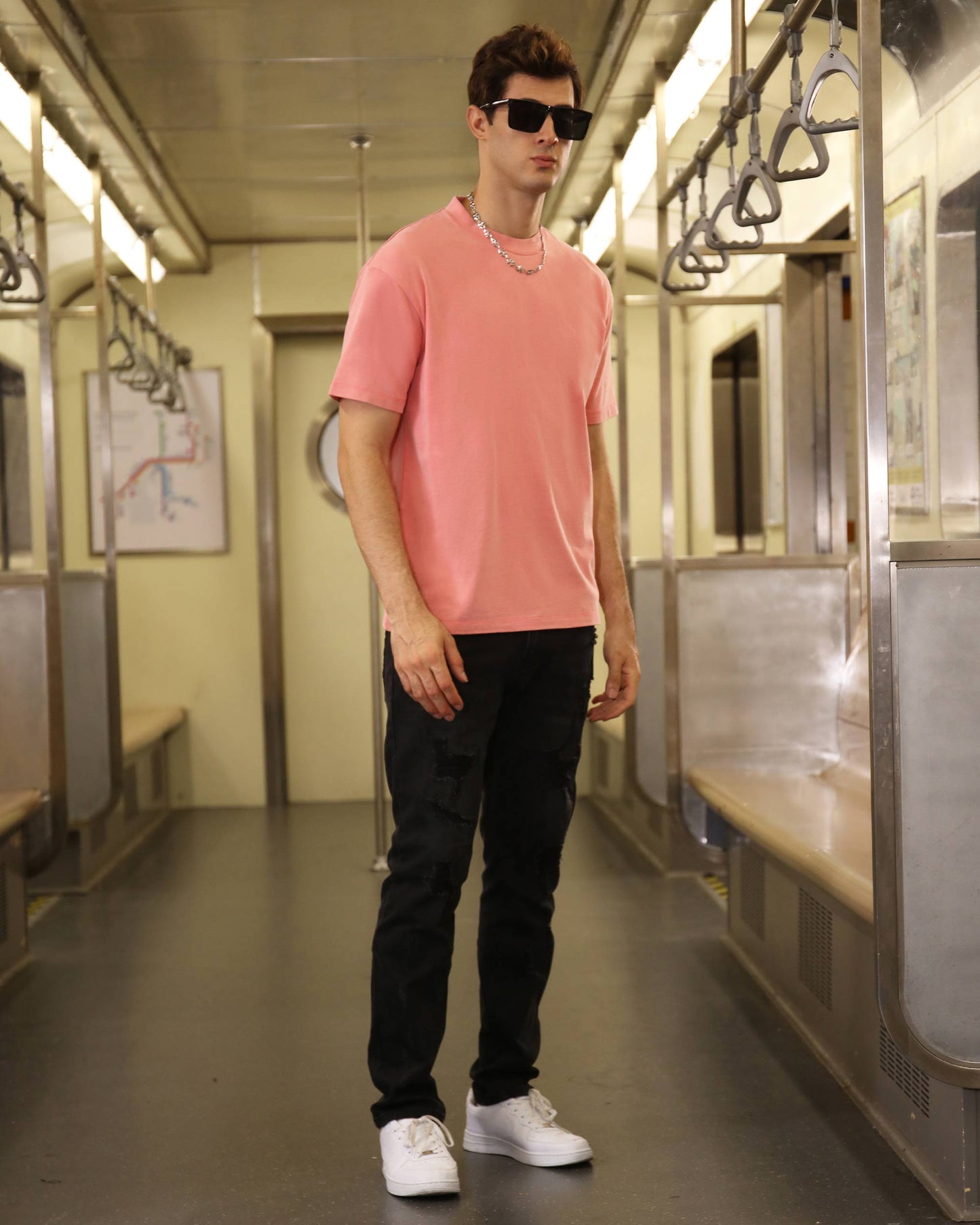 Model wearing a classic pink t-shirt paired with black cargo pants in a subway setting