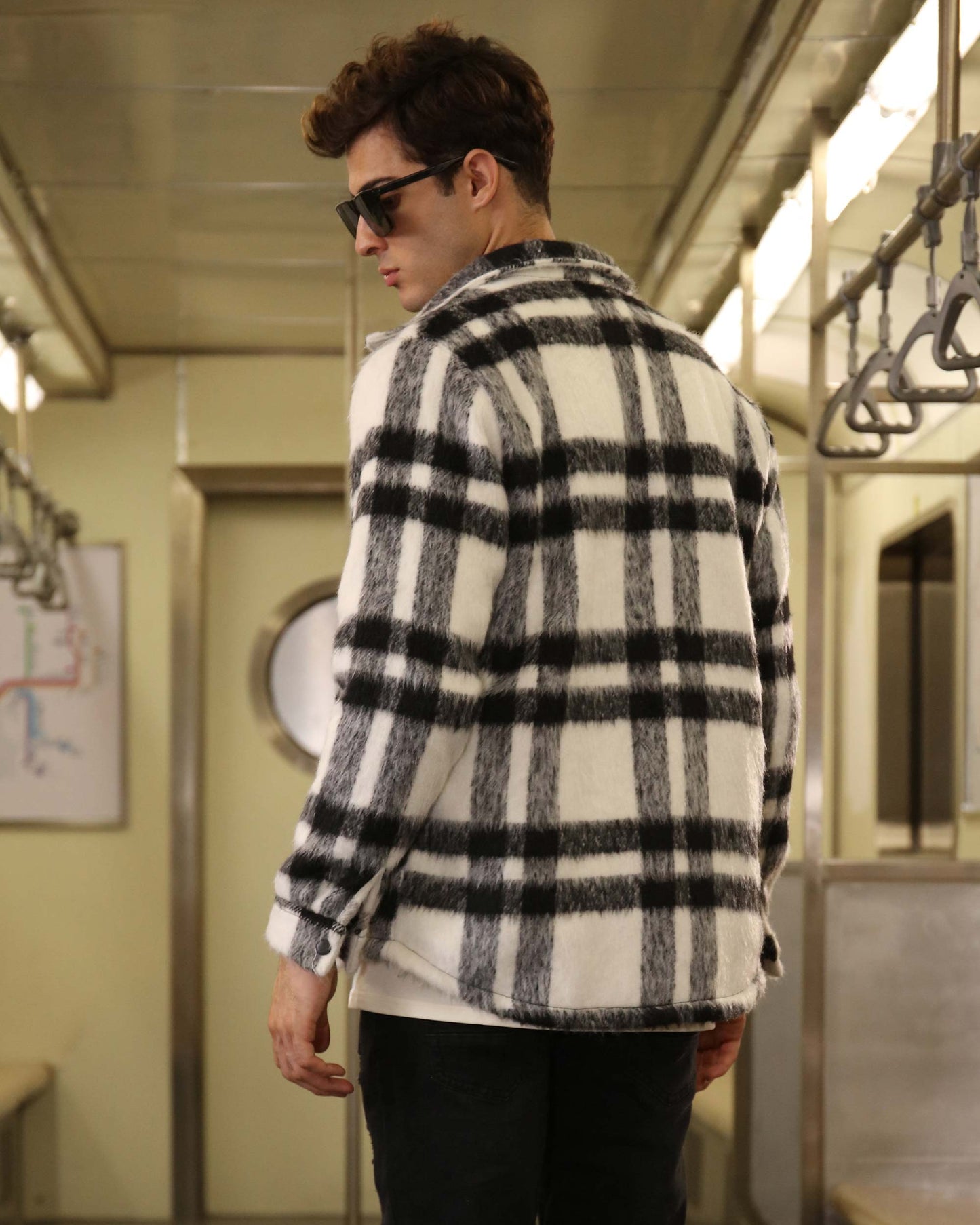 Man wearing Logeqi classic plaid moto jacket in black and white check pattern on subway train