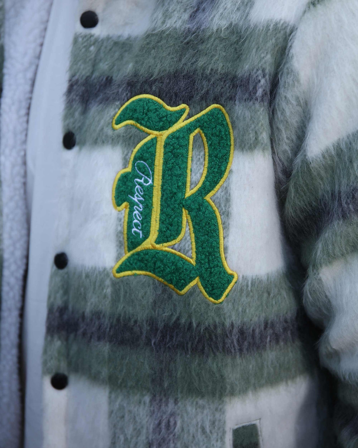 Close-up of Logeqi classic plaid moto jacket with green and white check pattern and embroidered letter R patch