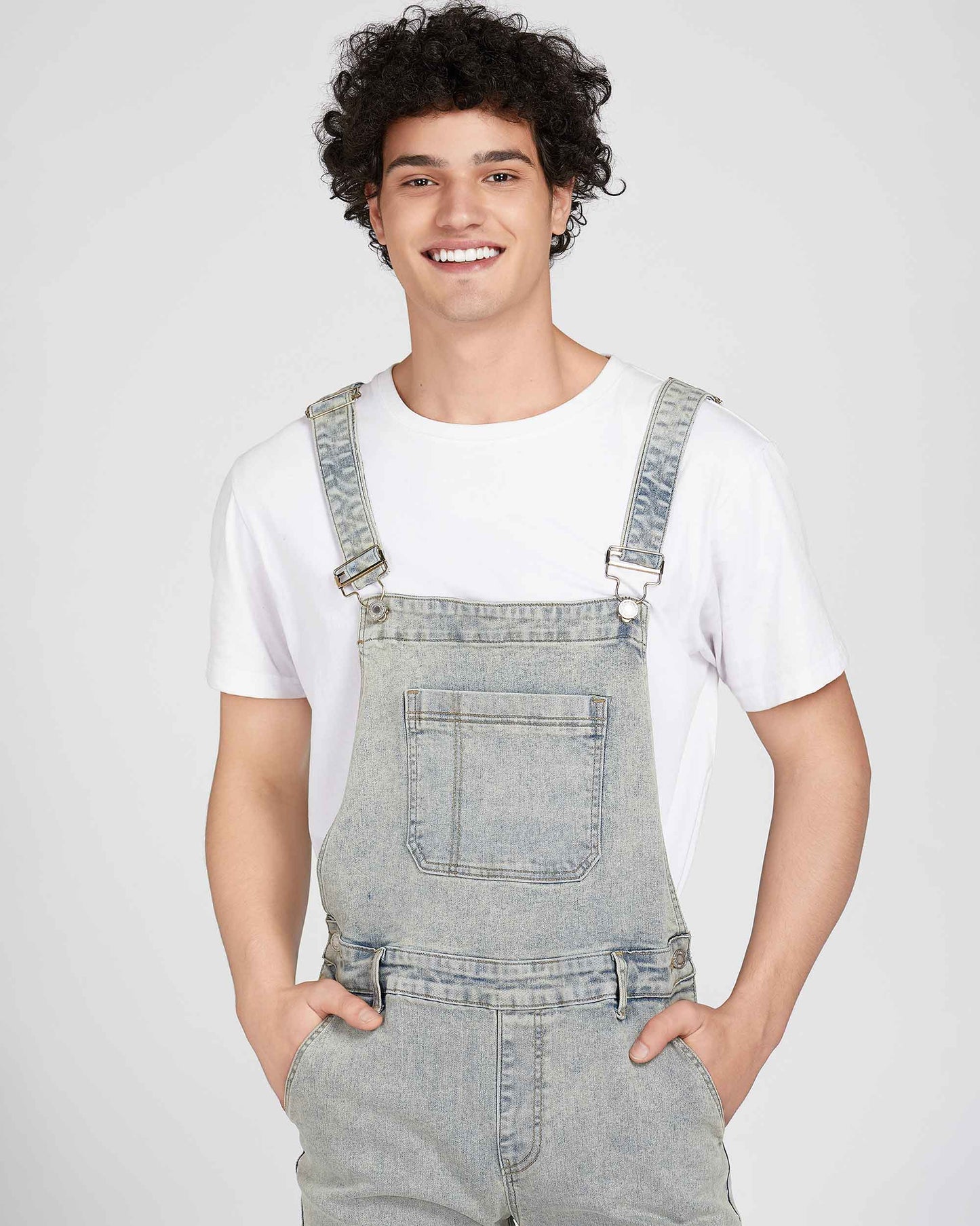 Logeqi classic ripped overalls in light denim worn by a smiling man with curly hair and white t-shirt