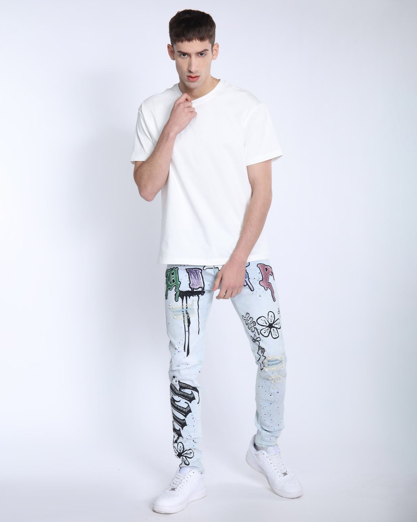 Logeqi comic painted ripped jeans worn by male model paired with white t-shirt and sneakers