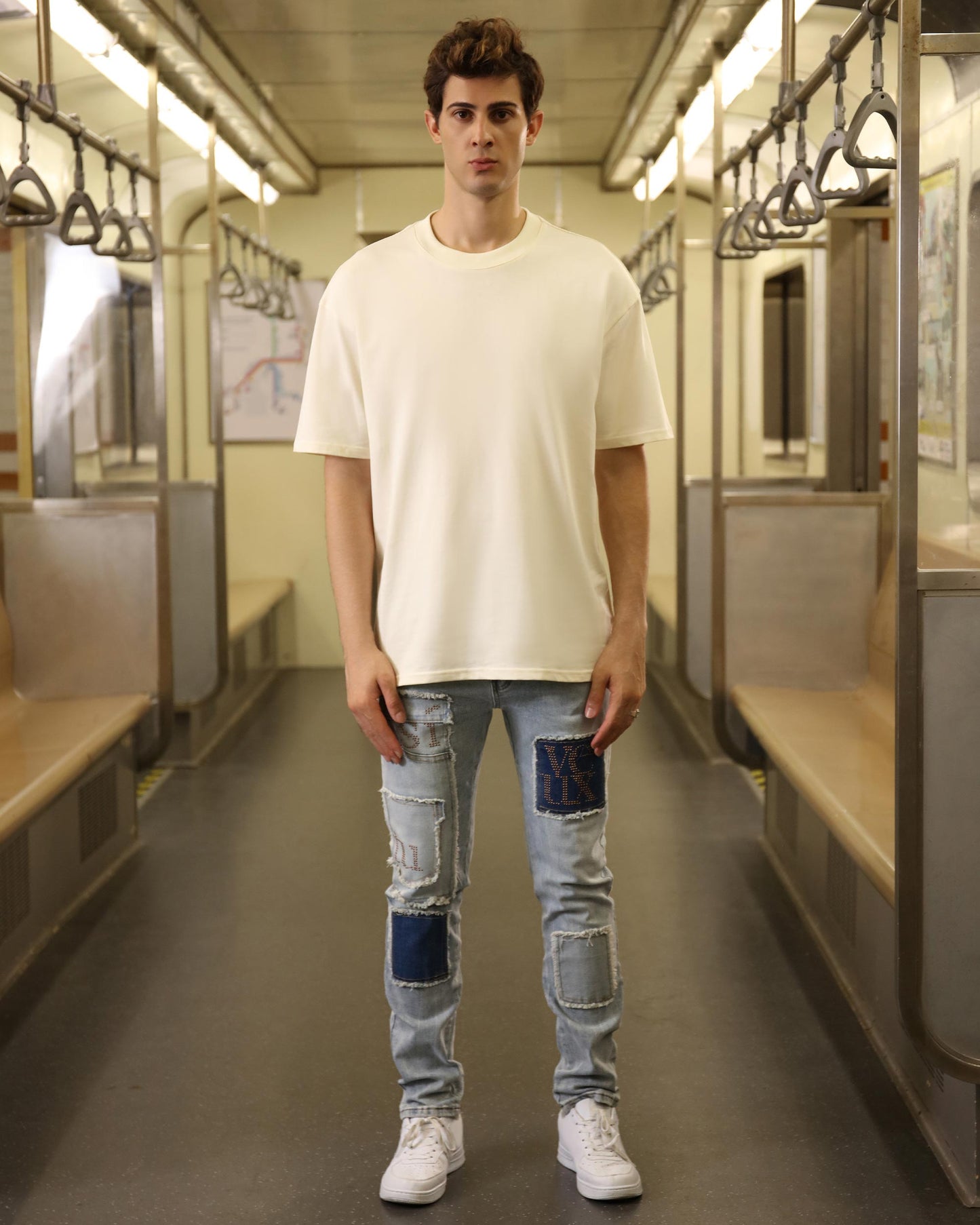 Model wearing a cream oversized t-shirt with distressed jeans in a subway setting