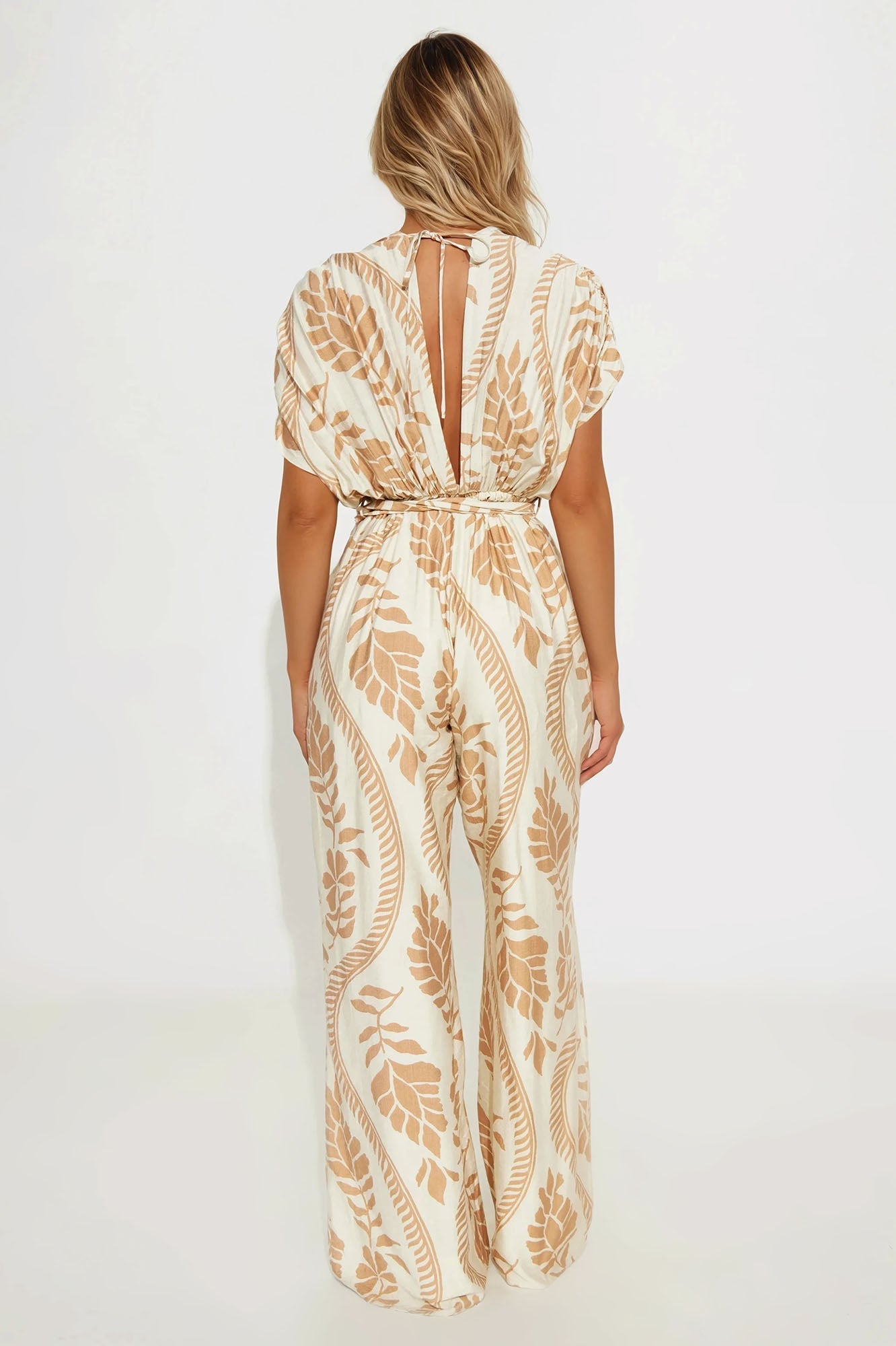 Back view of cream v-neck jumpsuit with floral print and open back detail from Fashion Nova