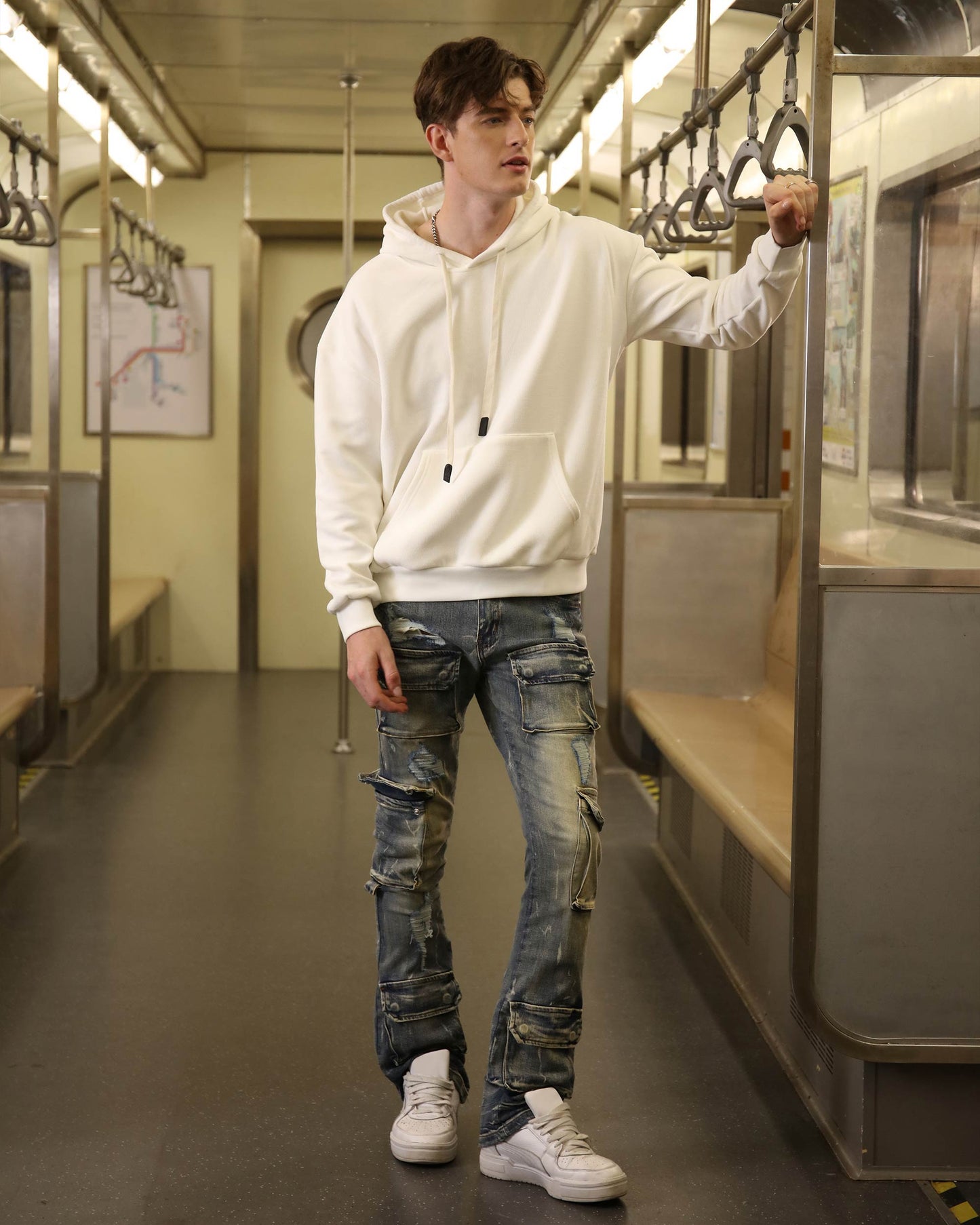 Model wearing Logeqi dark wash cargo jeans paired with a white hoodie in a subway setting