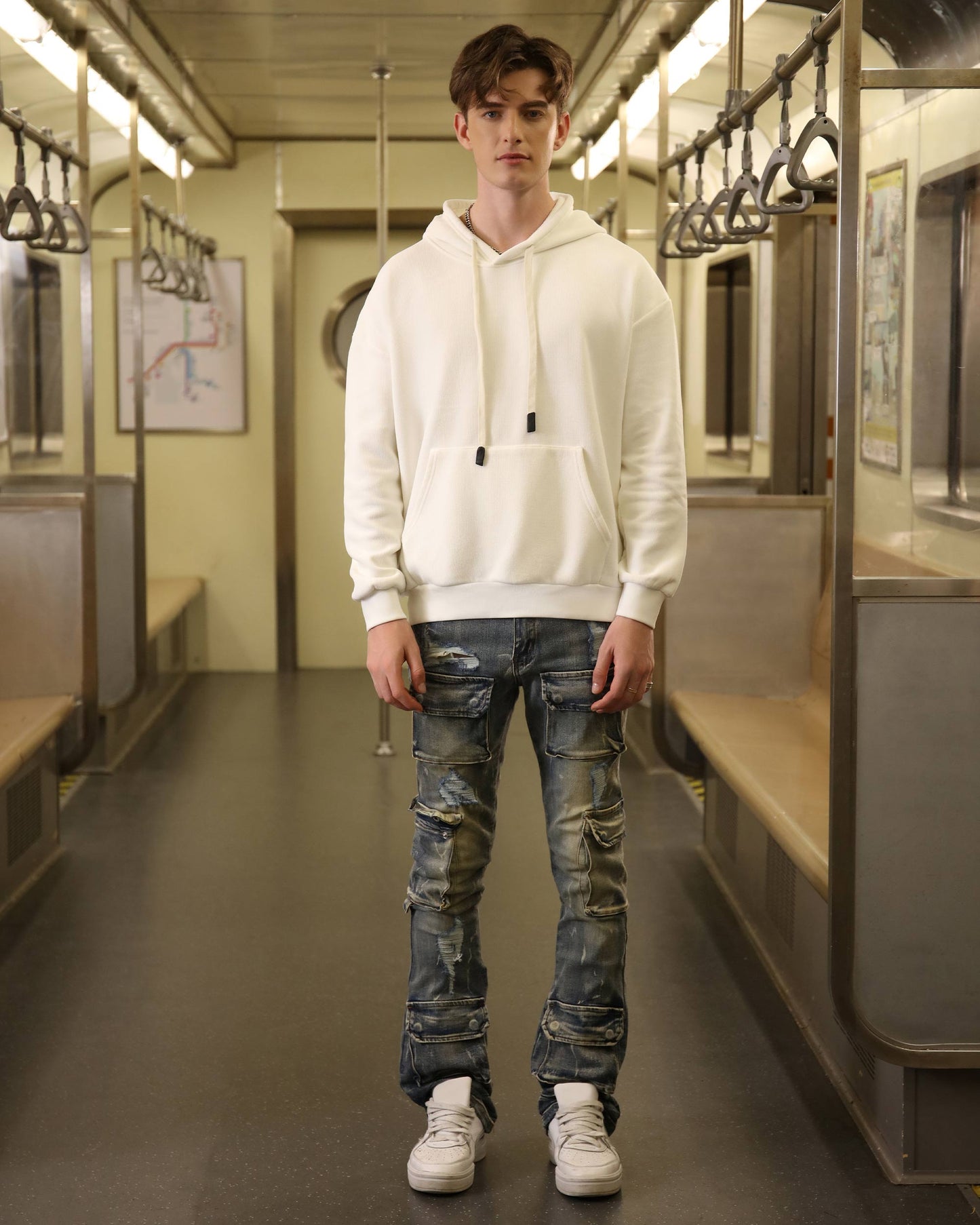 Logeqi dark wash cargo jeans with distressed details, styled with a white hoodie in a subway setting