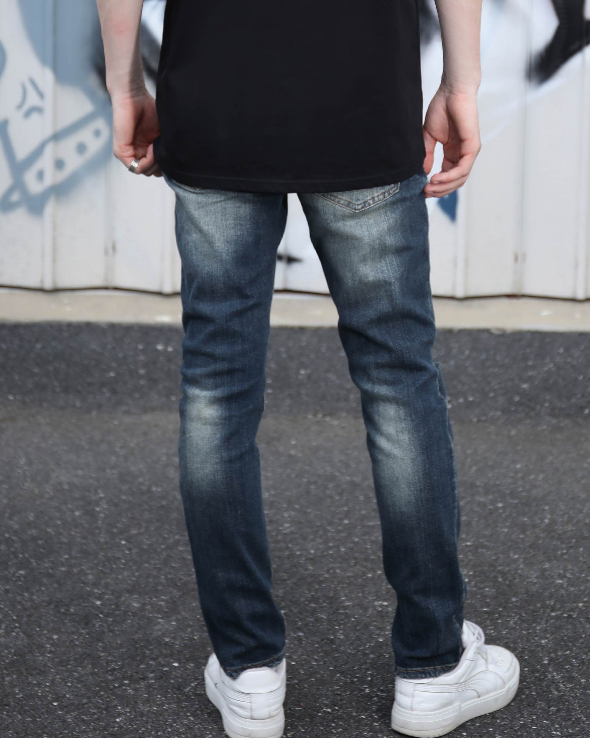 Logeqi slim fit ripped jeans men styled with white sneakers and black shirt from the back