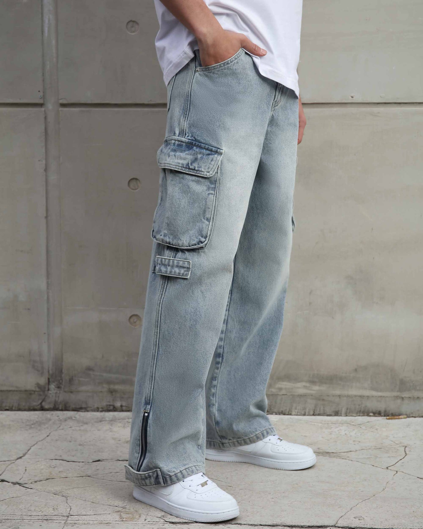 Logeqi distressed blue baggy jeans with cargo pockets and side zipper detail worn with white sneakers