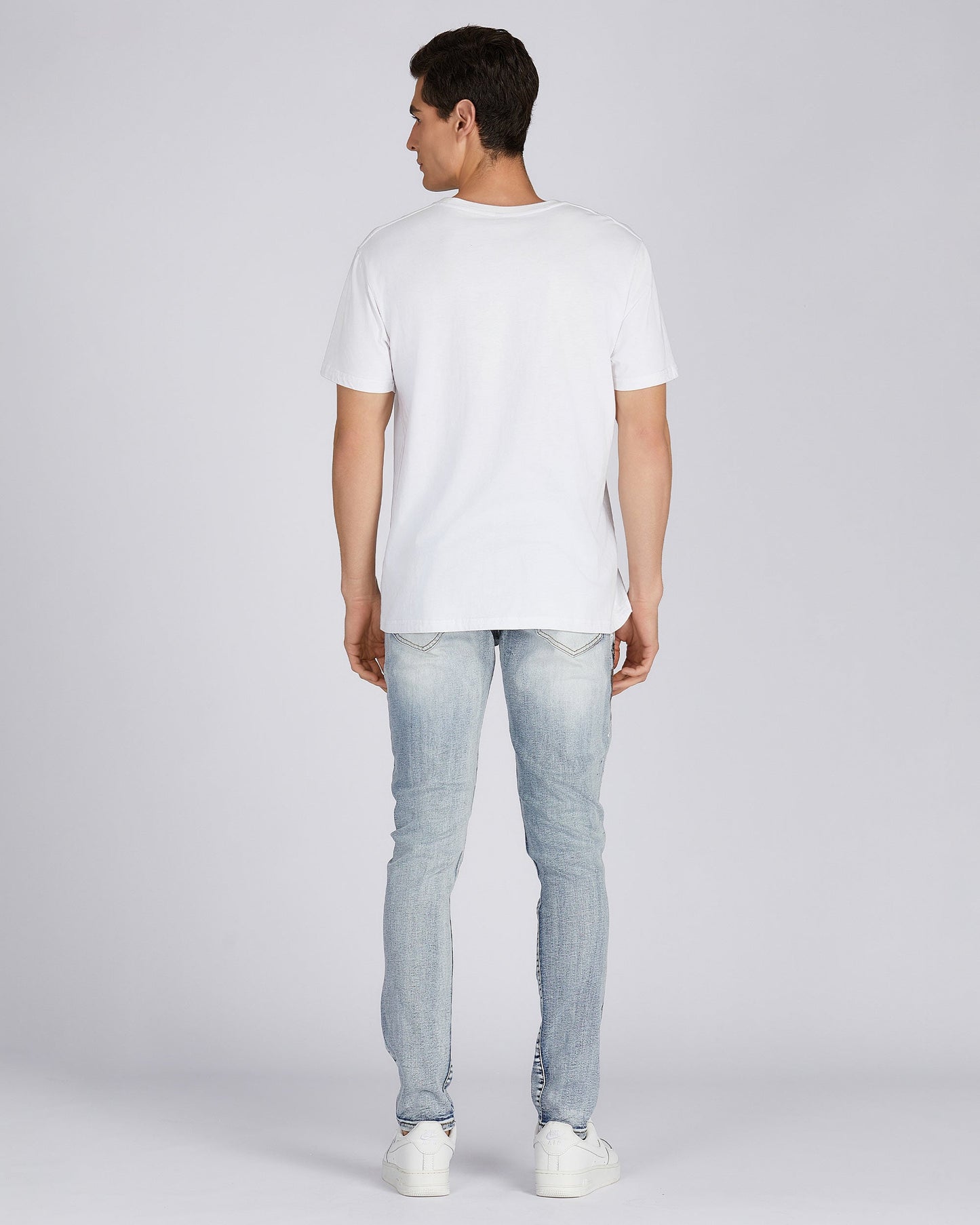 Logeqi distressed blue jeans shown on a model from the back with a white t-shirt and sneakers