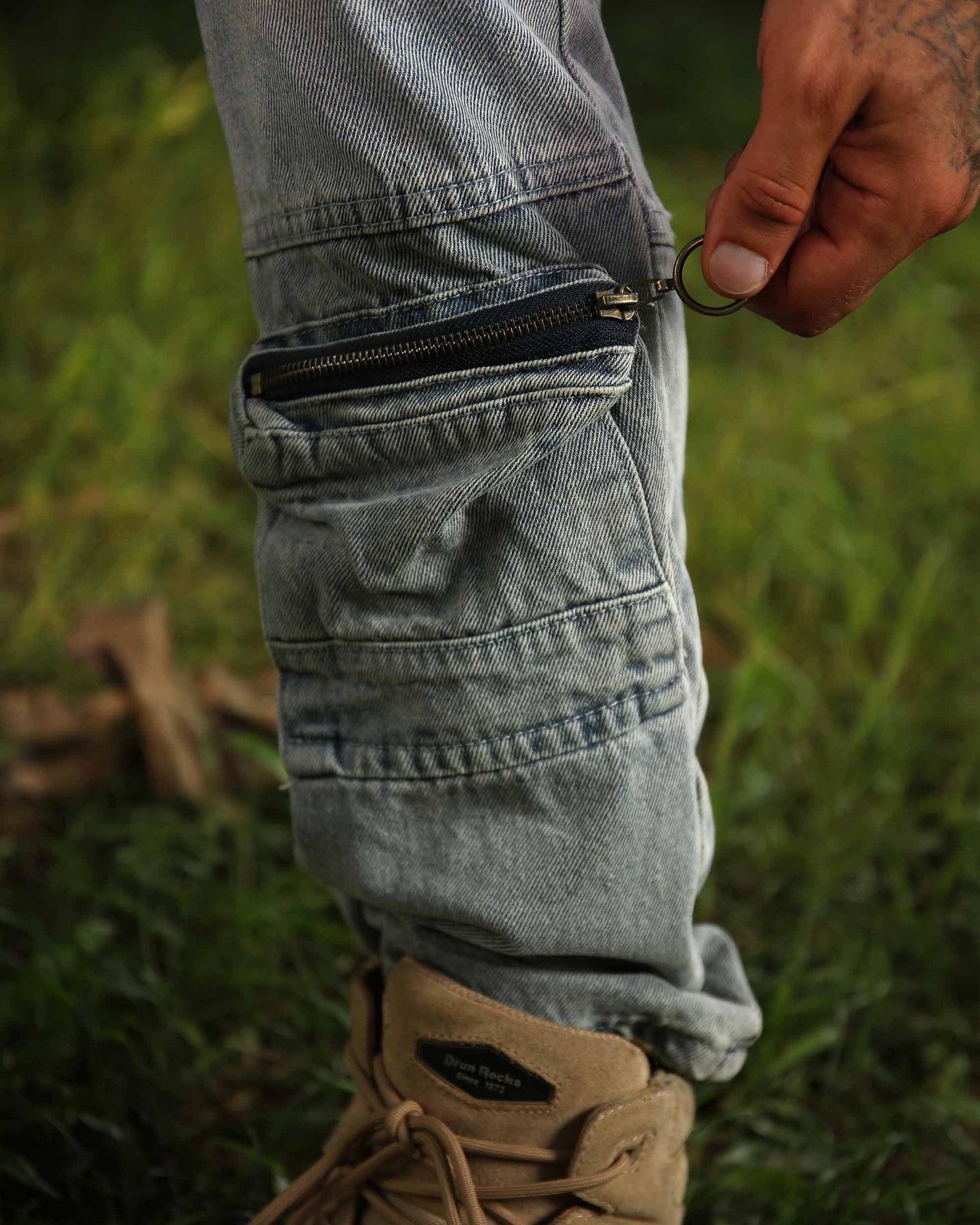 Close-up of Logeqi distressed cargo jeans pocket with zipper detail worn outdoors