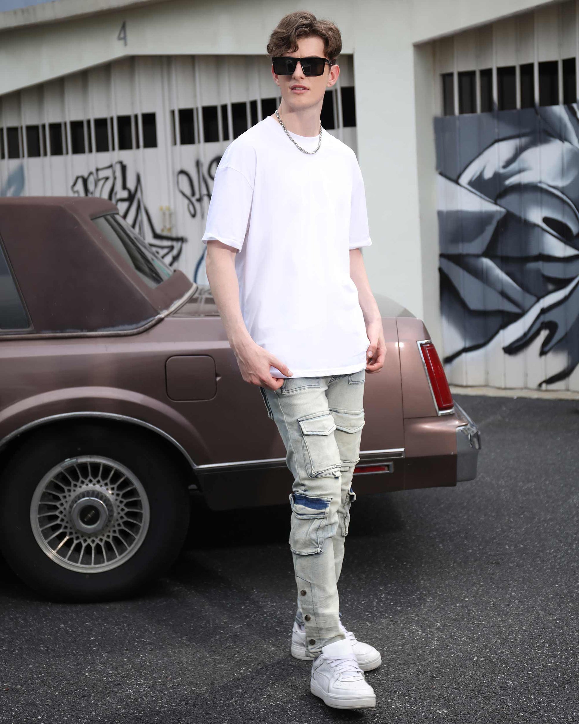 Male model wearing Logeqi distressed cargo jeans men in light gray paired with white sneakers and oversized white t-shirt