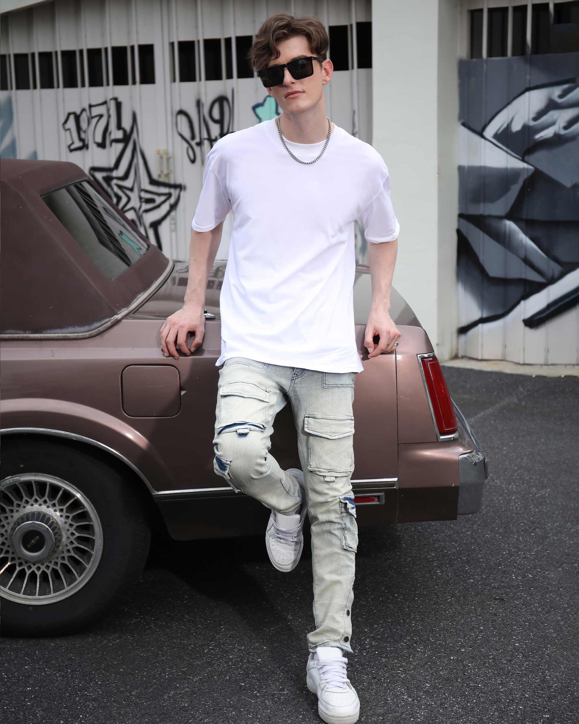 Logeqi distressed cargo jeans men in light wash worn by male model leaning on vintage car