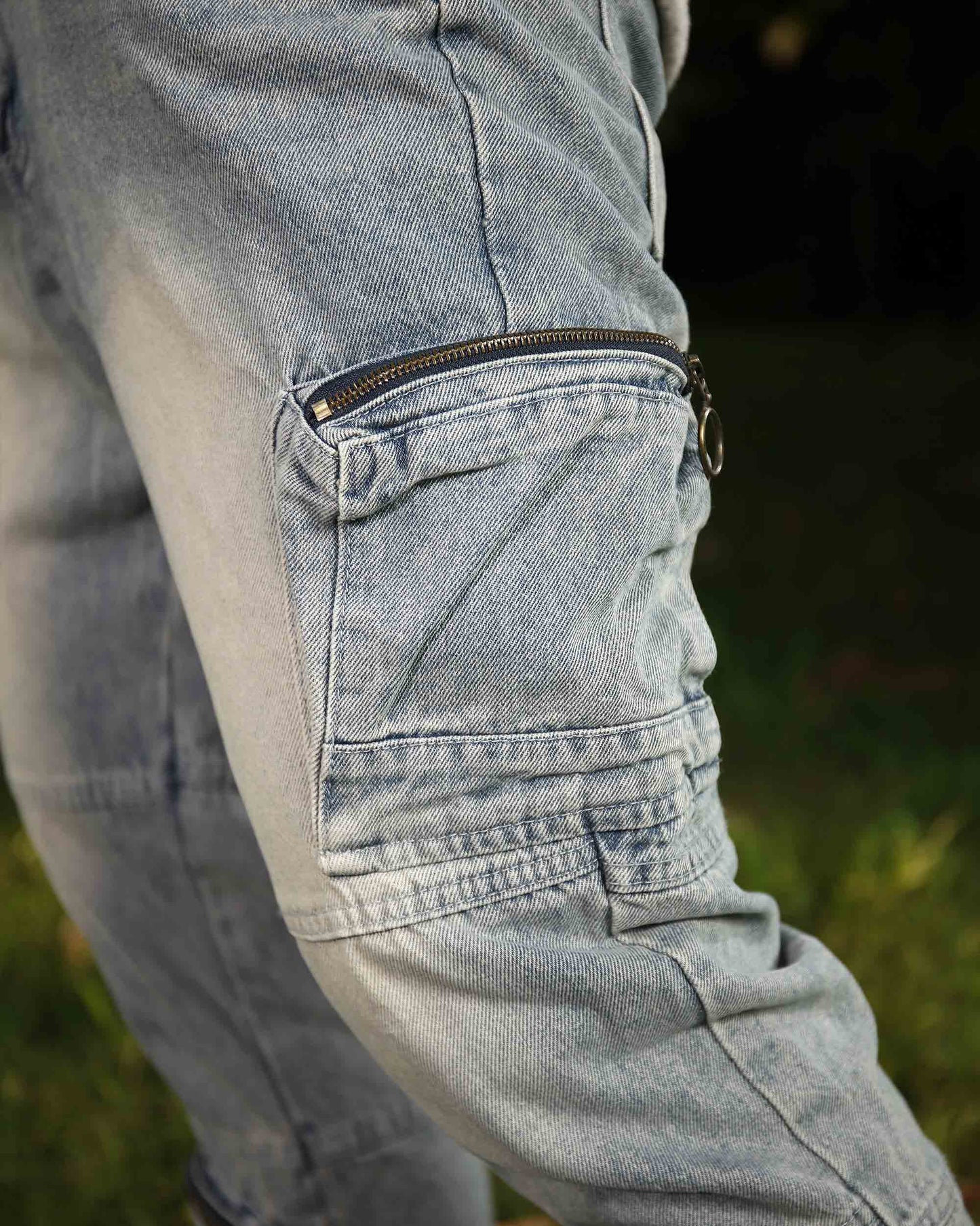 Close-up of Logeqi distressed cargo jeans pocket with zipper detail on light blue denim