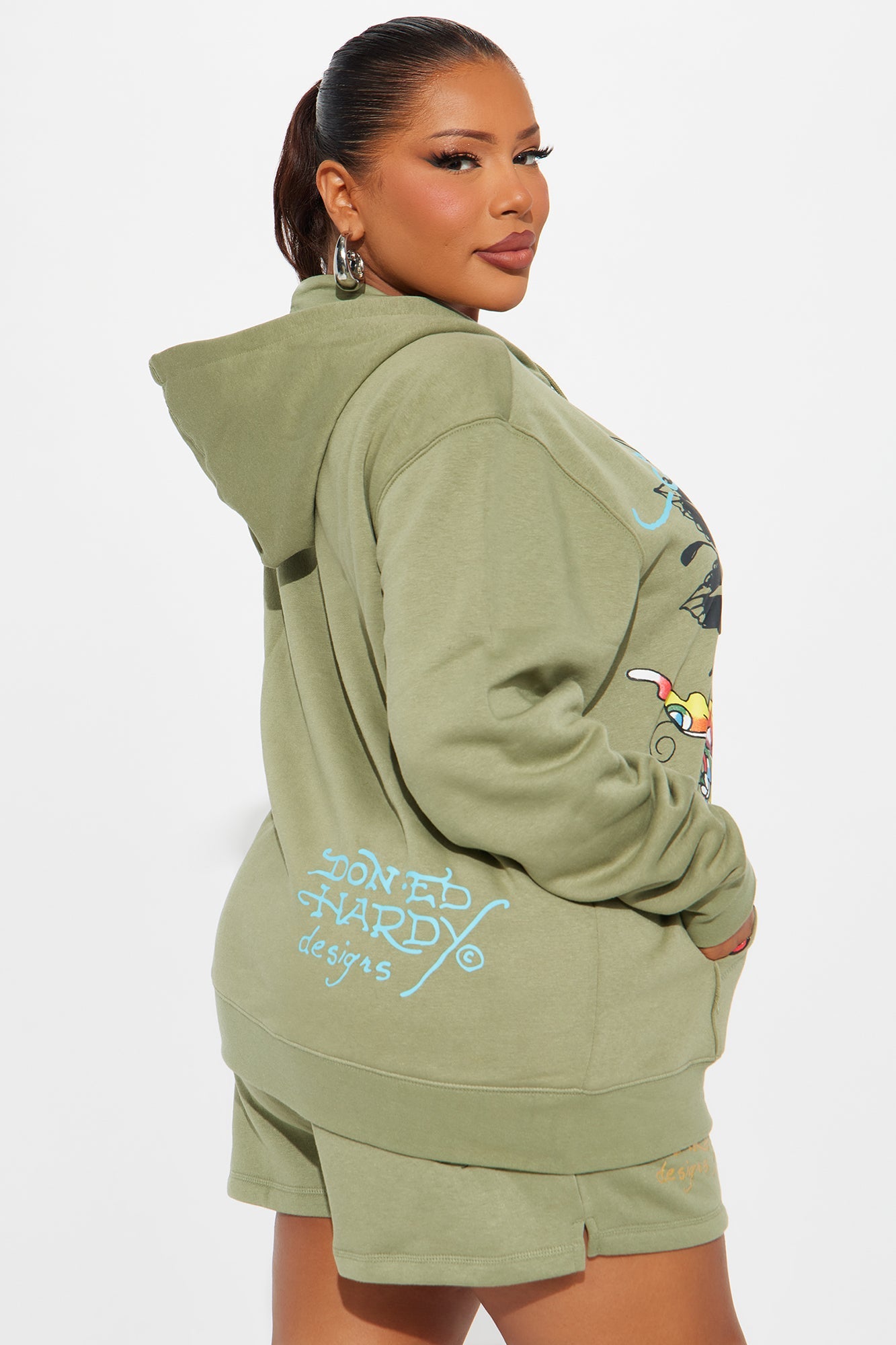 Model wearing Ed Hardy butterfly hoodie in olive green with colorful graphic designs and matching shorts