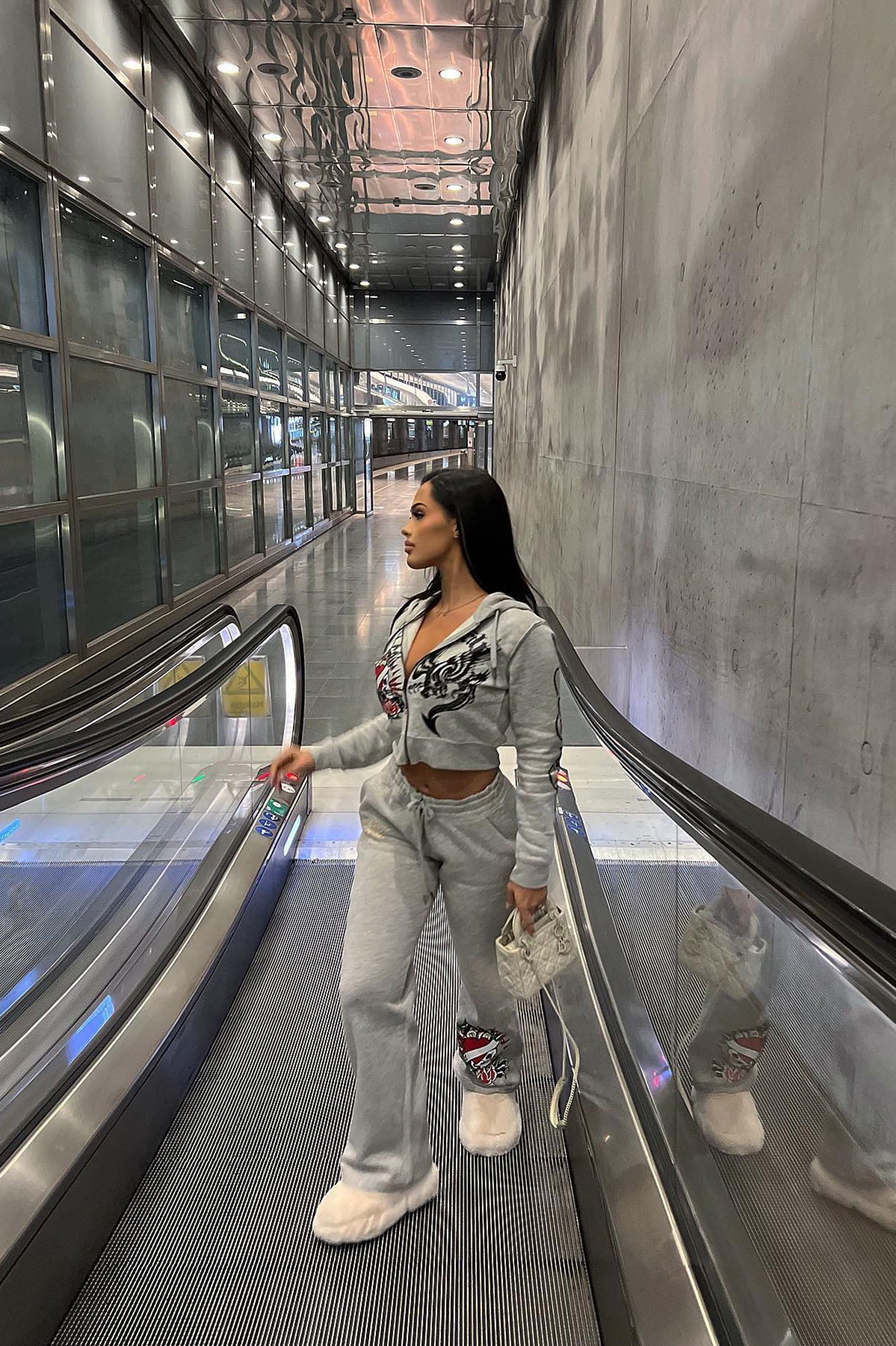 Model wearing Ed Hardy heart of roses hoodie with matching gray sweatpants in a modern setting