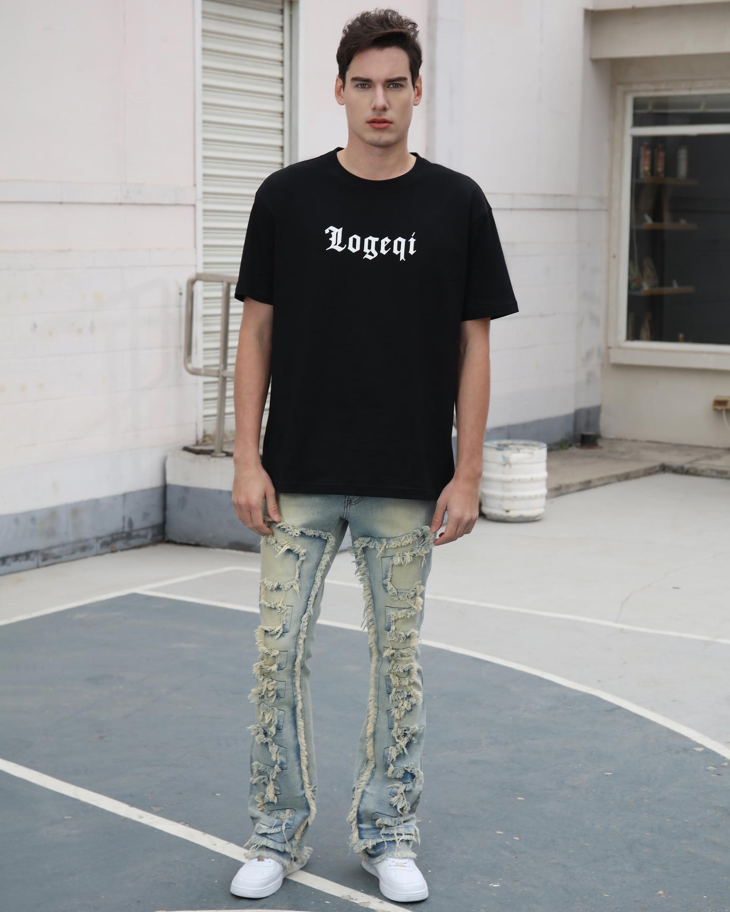 Man wearing Logeqi fringe flared jeans with distressed details and a black logo t-shirt