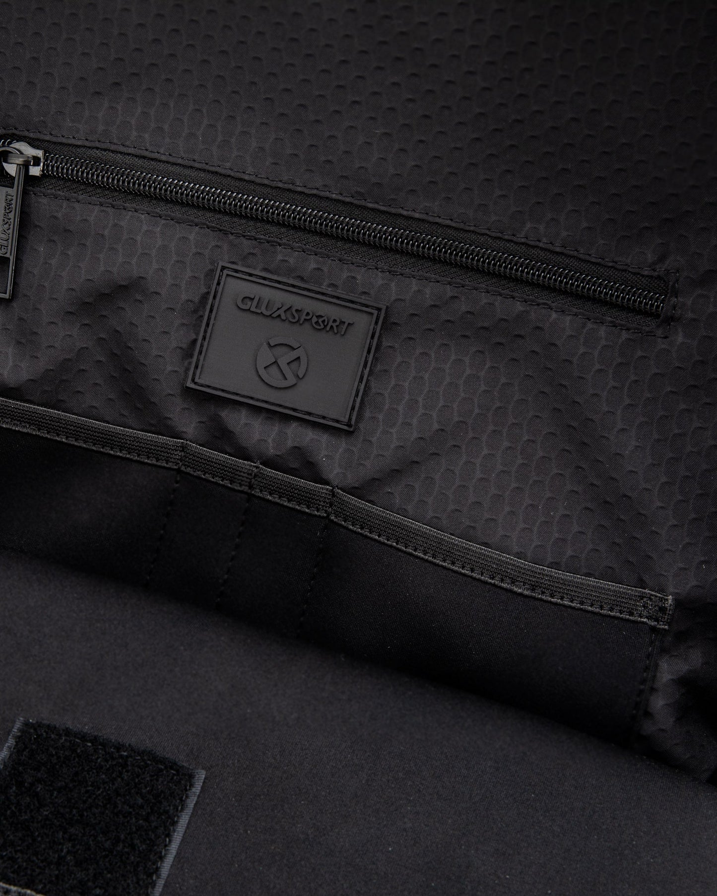 Interior view of the Glux men's sports backpack with zip pocket and logo detail