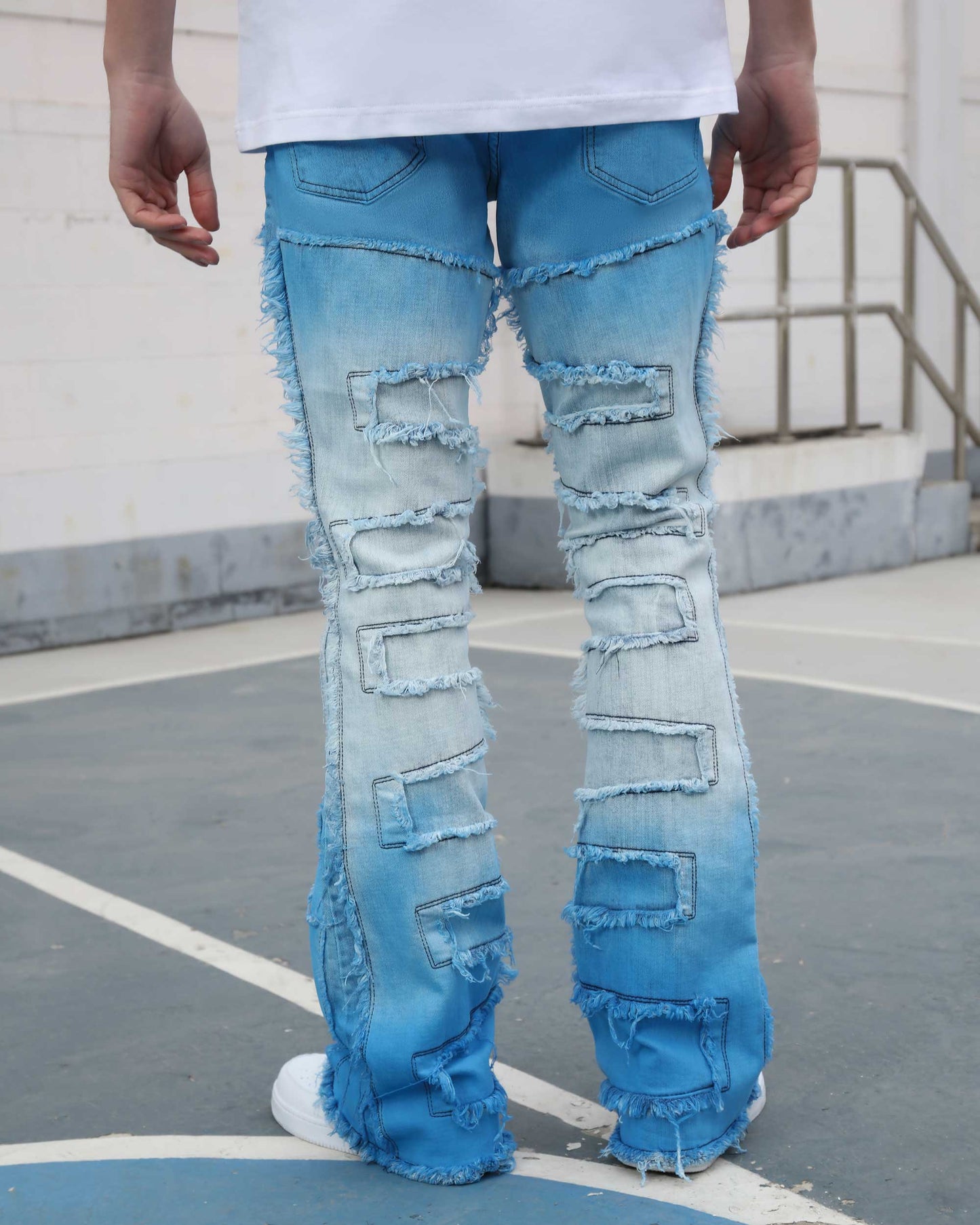 Logeqi gradient blue flare jeans with distressed patches and frayed hems shown from the back