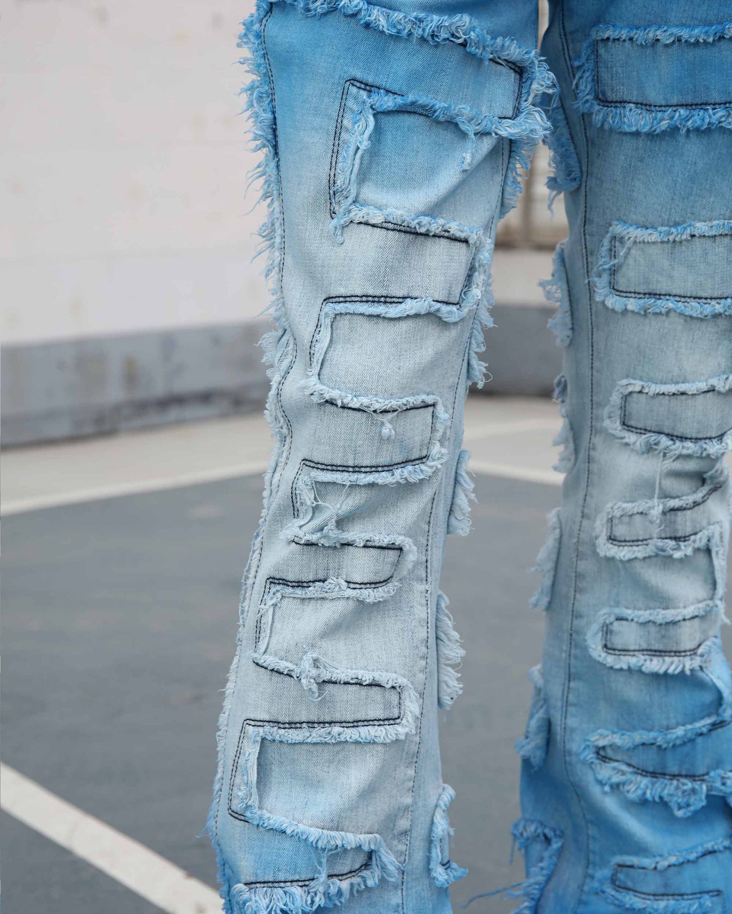 Logeqi gradient blue flare jeans with distressed patches and frayed edges on an outdoor pavement