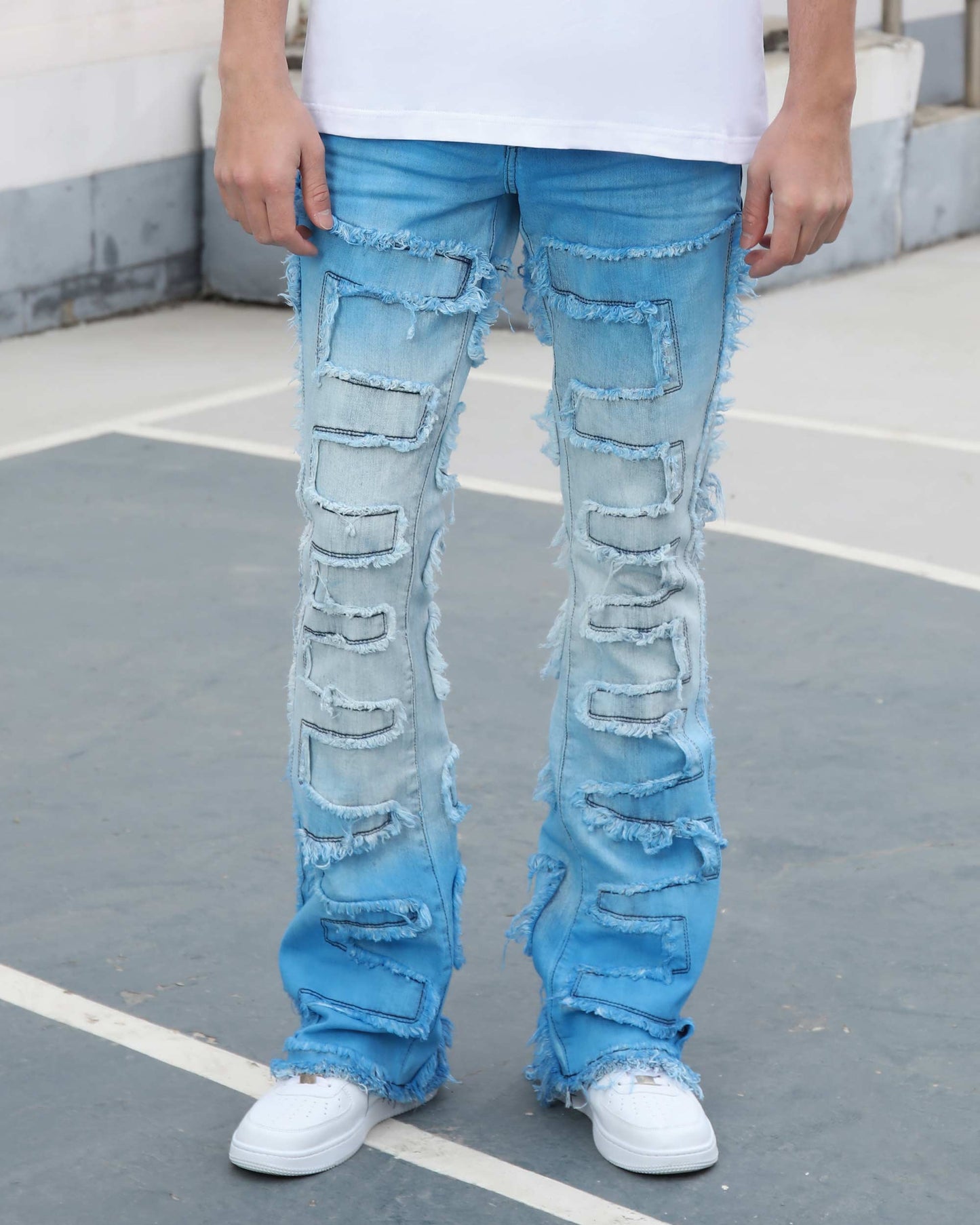Logeqi gradient blue flare jeans with distressed patchwork design worn with white sneakers