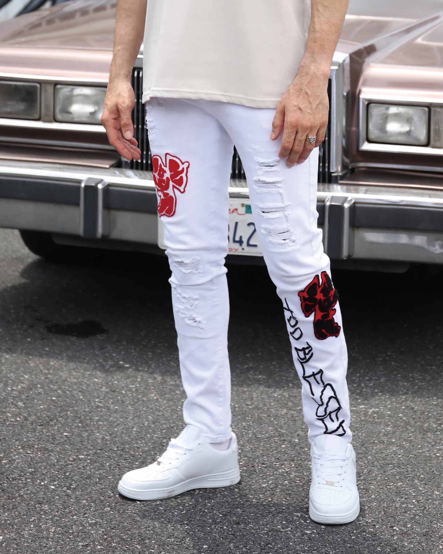 White graffiti embroidered jeans with red floral designs and distressed details for a stylish look
