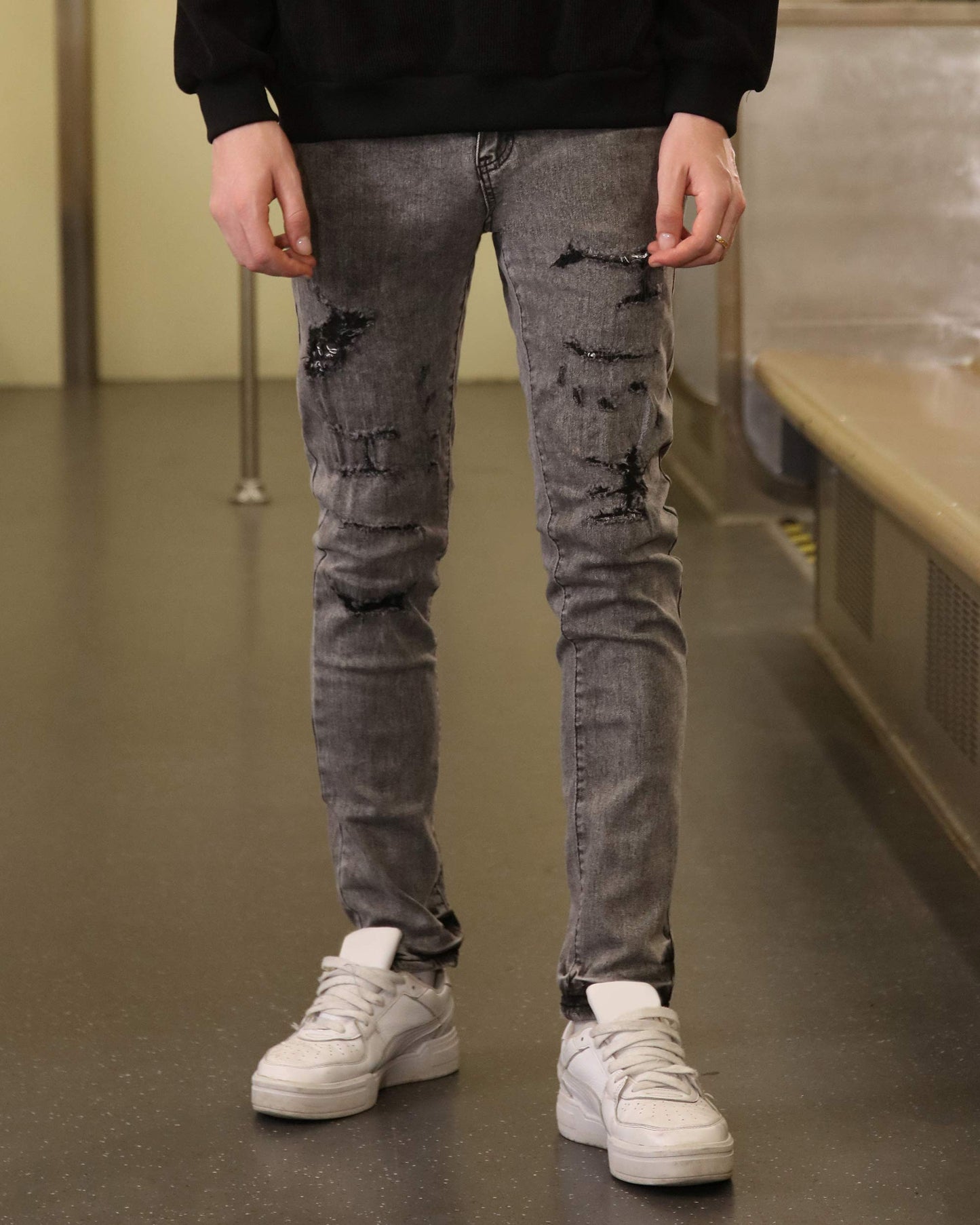 Logeqi gray ripped jeans men styled with white sneakers and black sweatshirt in urban setting