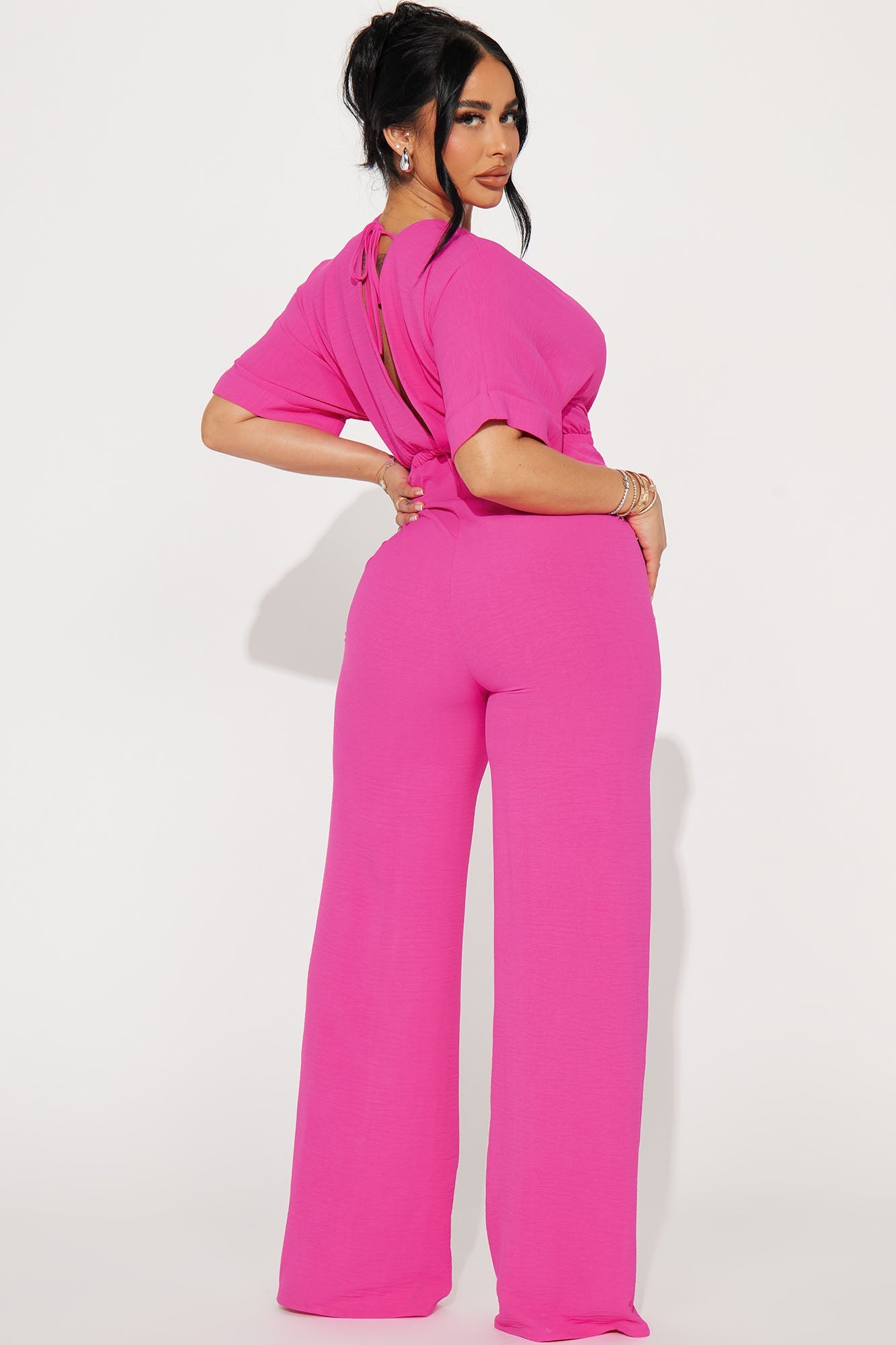 Back view of a stylish hot pink jumpsuit for women with a trendy cut-out design